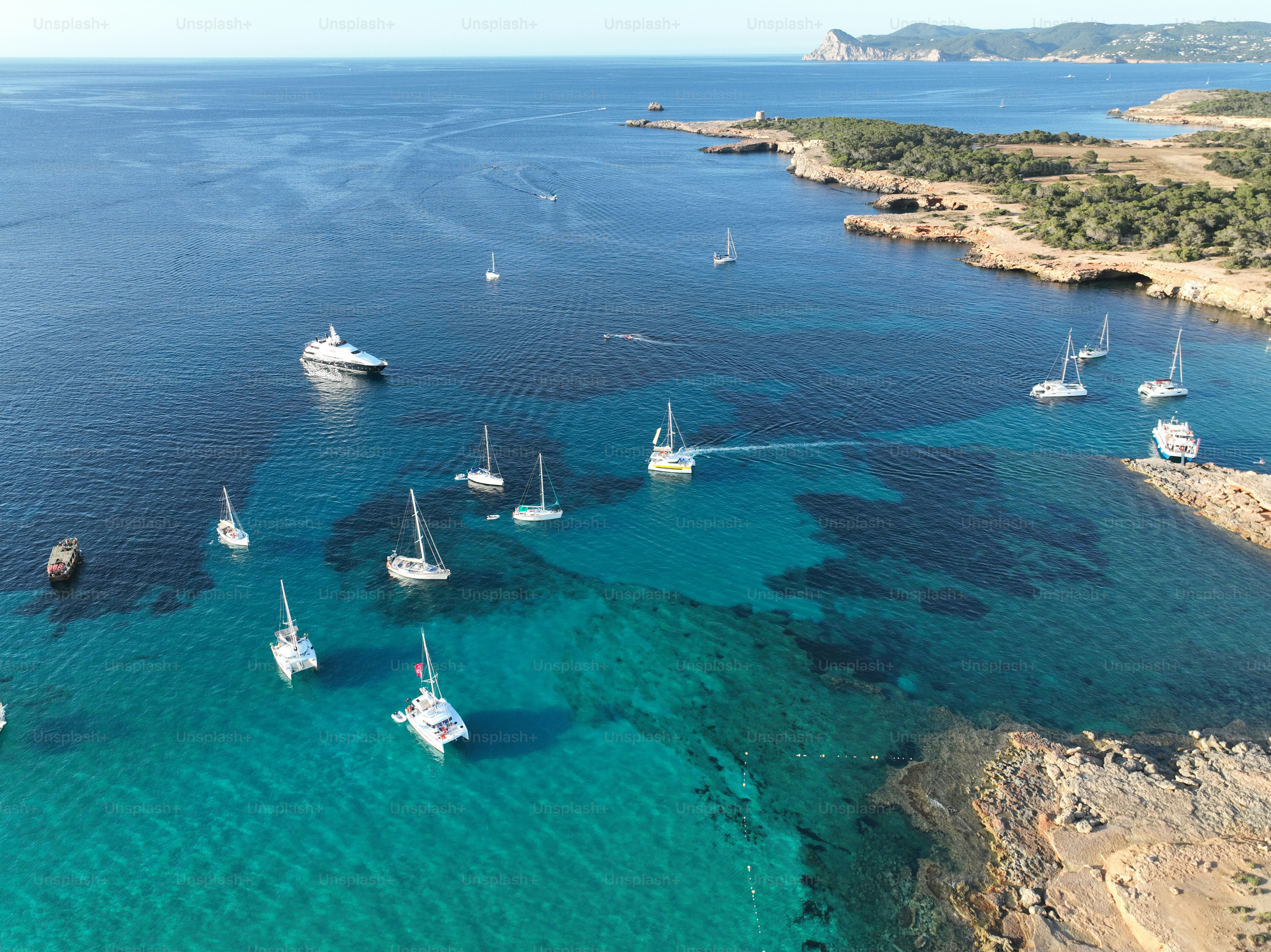 Aerial view of Ibiza beach in summer, Cala Comte beach. Boats and yachts in crystal clear water.