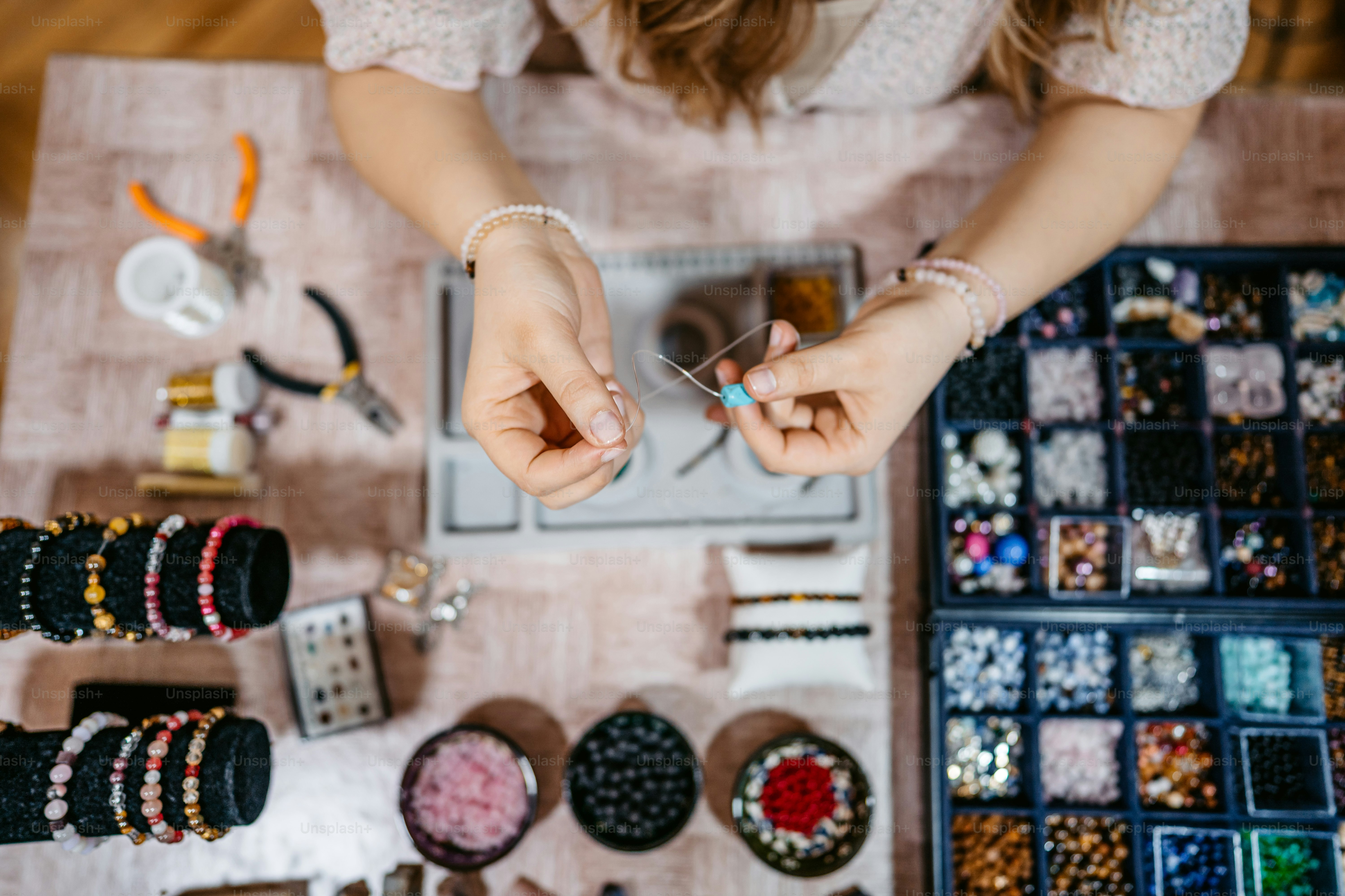 Young woman making jewelry with beads in her home.