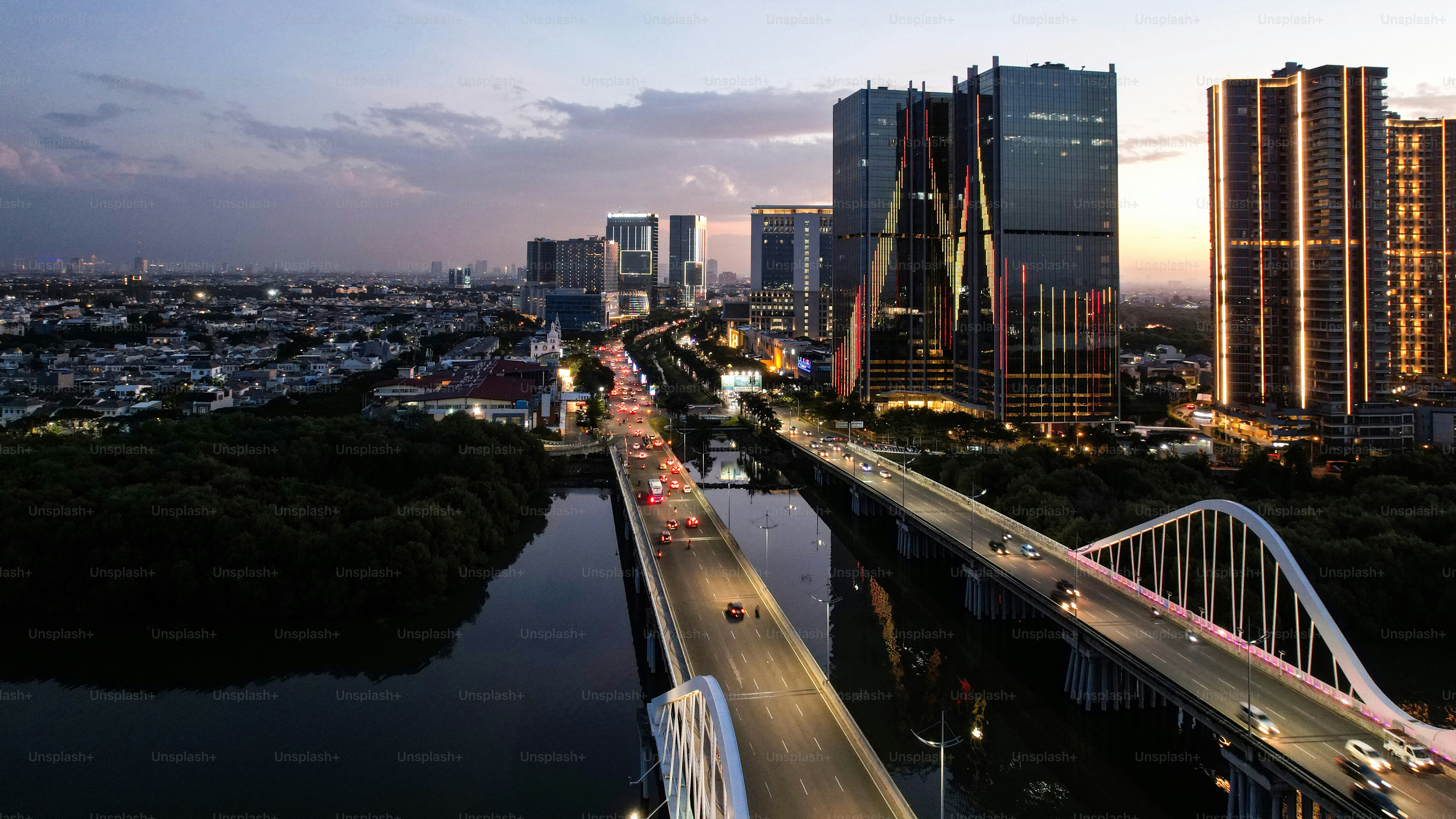 Aerial view of Pantai Indah Kapuk Avenue Bridge Jakarta. a Largest bridge in Jakarta. With Jakarta cityscape and noise cloud when sunset.