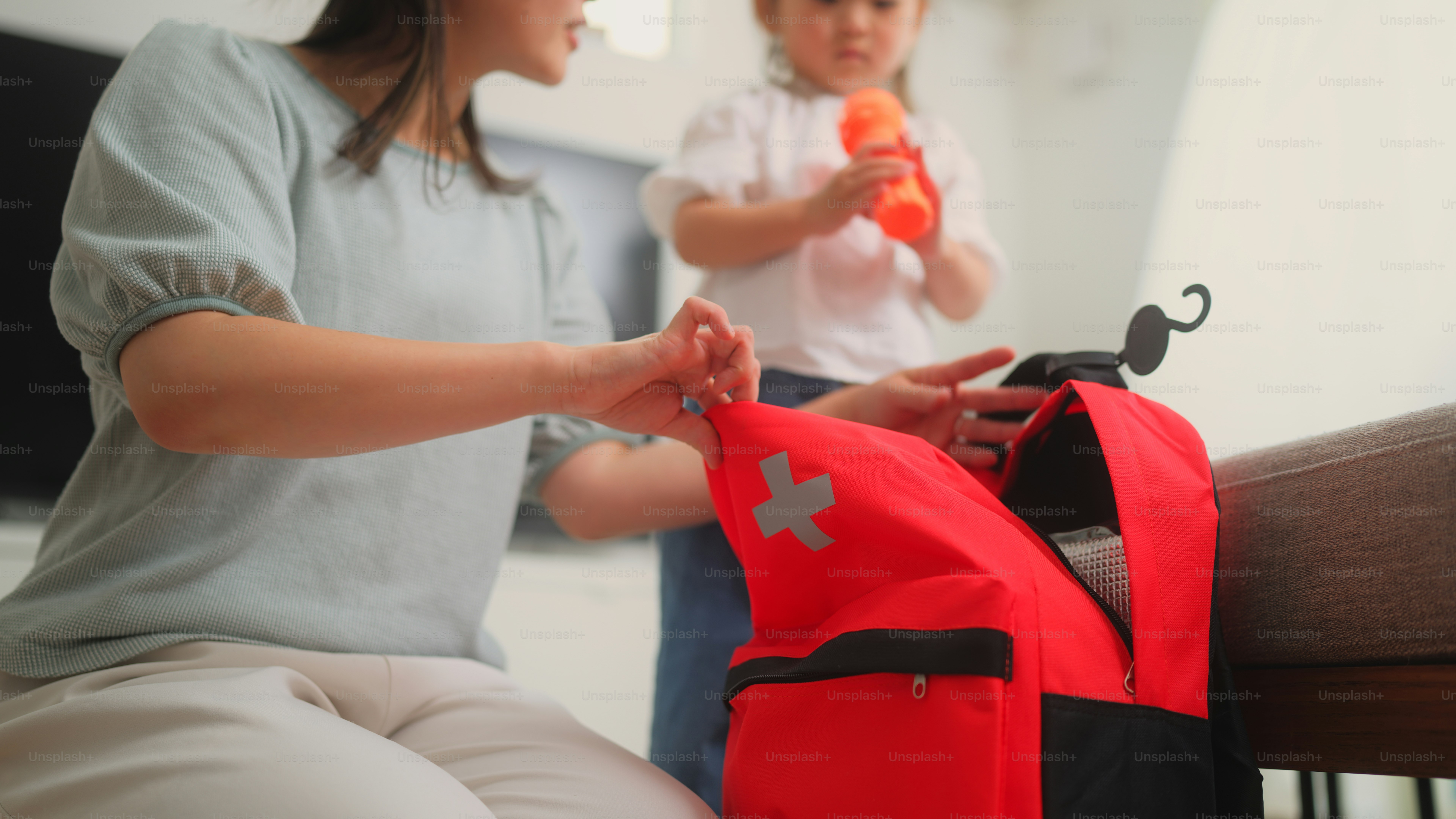 A mother is checking the items and preparing an emergency bag in the living room at home.