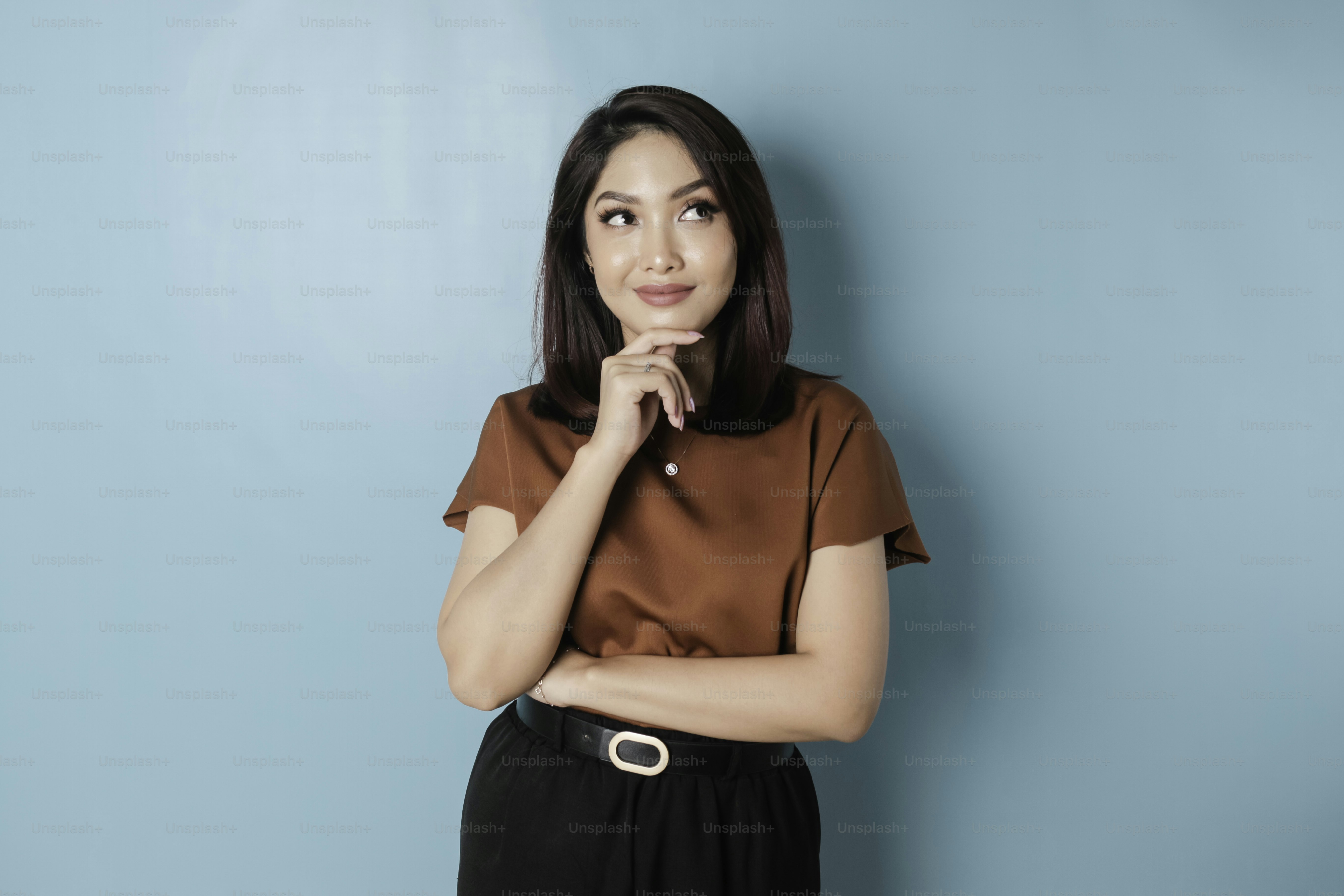 Portrait of a thoughtful young casual girl wearing a brown shirt looking aside isolated over blue background