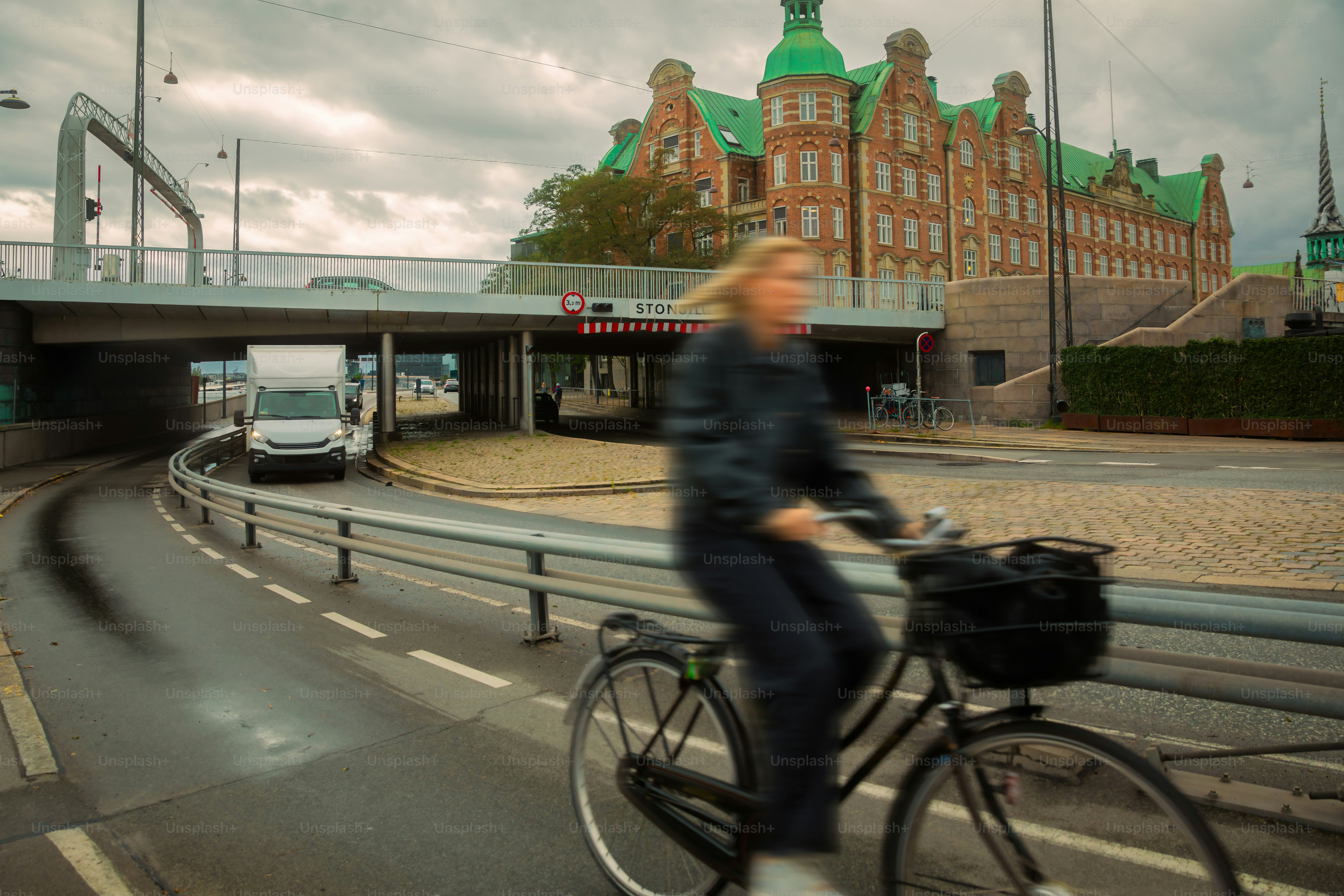 Blurred motion of woman using bicycle and Copenhagen city skyline on background.