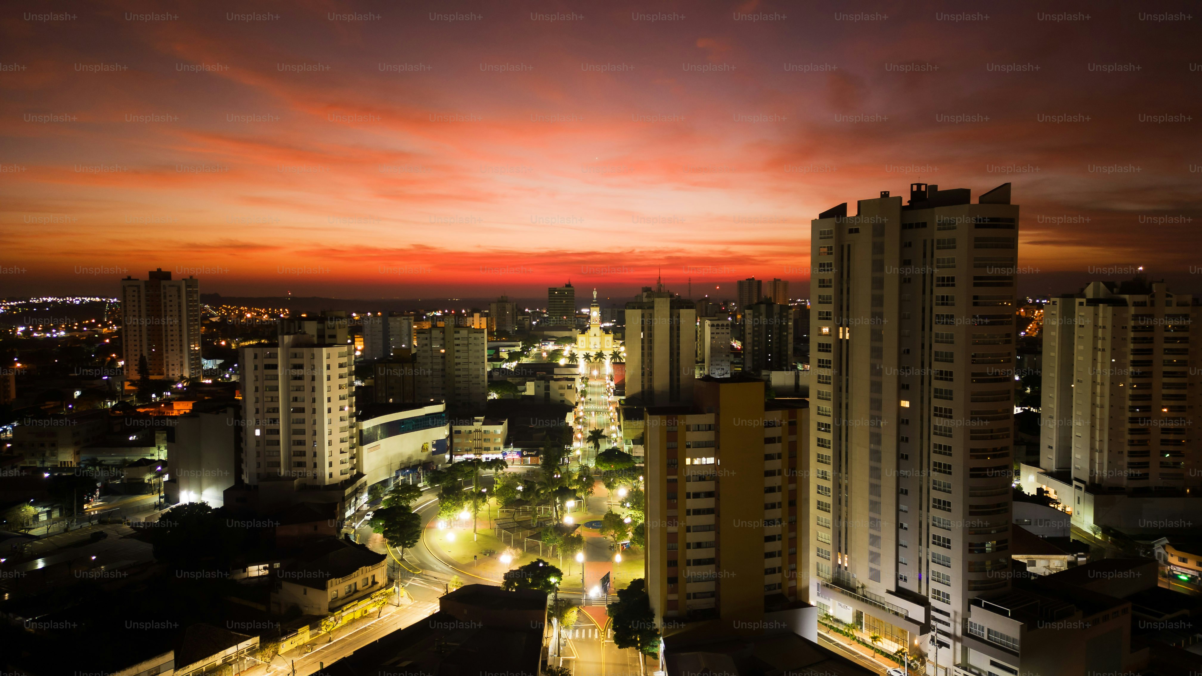 Autumn dawn with orange red sky in the city of Apucarana, with the street lights on and with a view of some buildings in the city center.