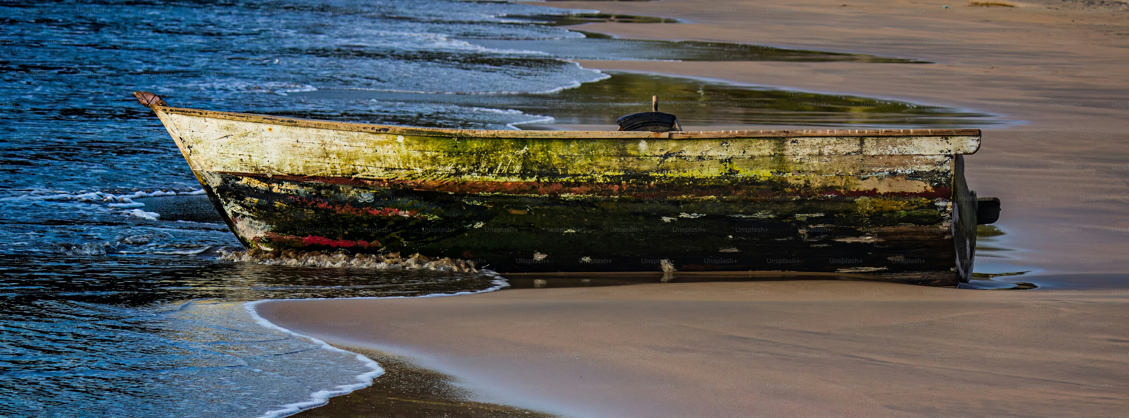 An abandoned boat on the shore under the sky of sunrise. Near the beach. Sunset sky in the wild nature. Beautiful colors. Serenity.