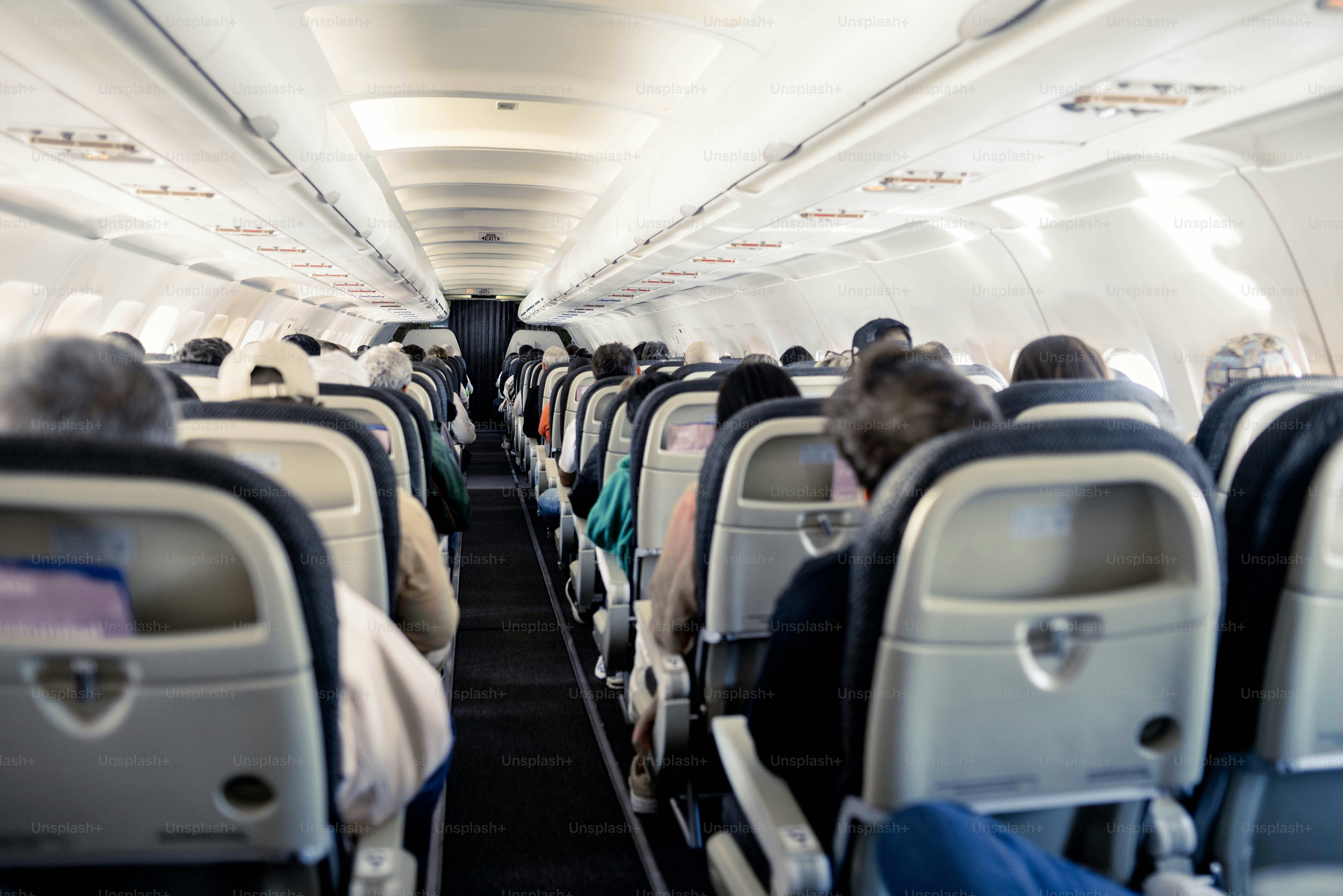 Interior of an aeroplane cabin with rows of seats down the aisle