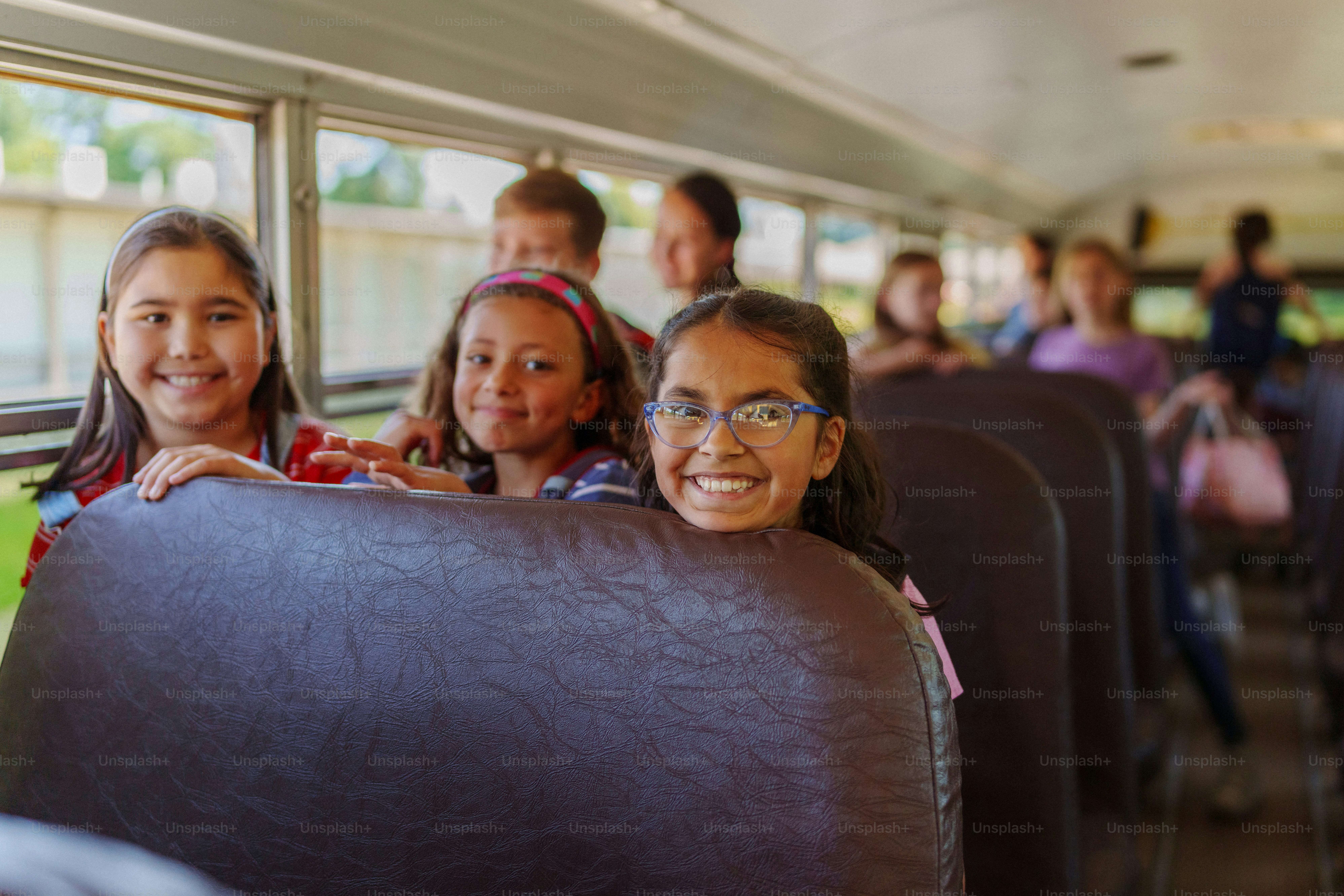A multiracial group of elementary age girls sit together on a school ...