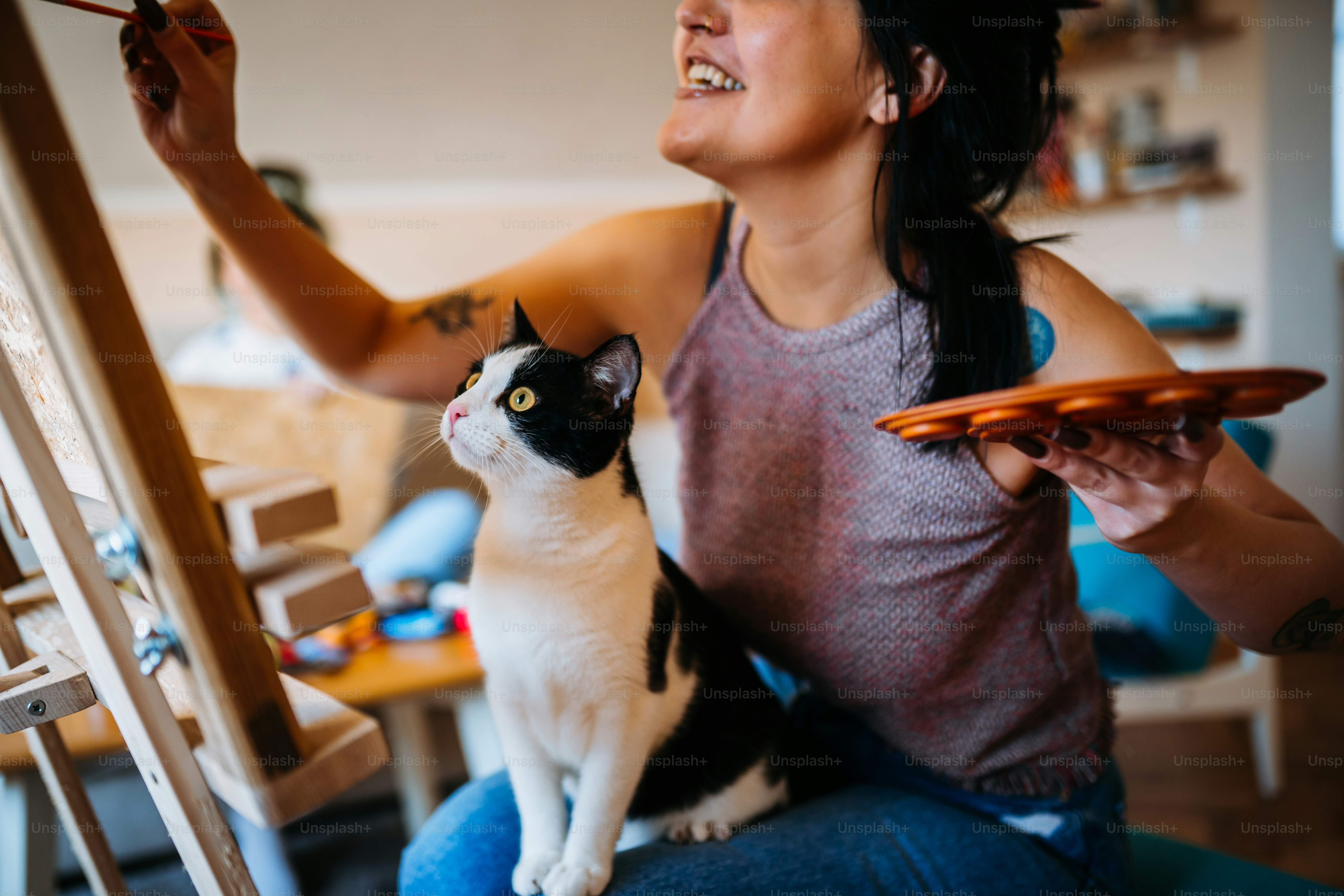 Young female artist painting with a cat in her lap
