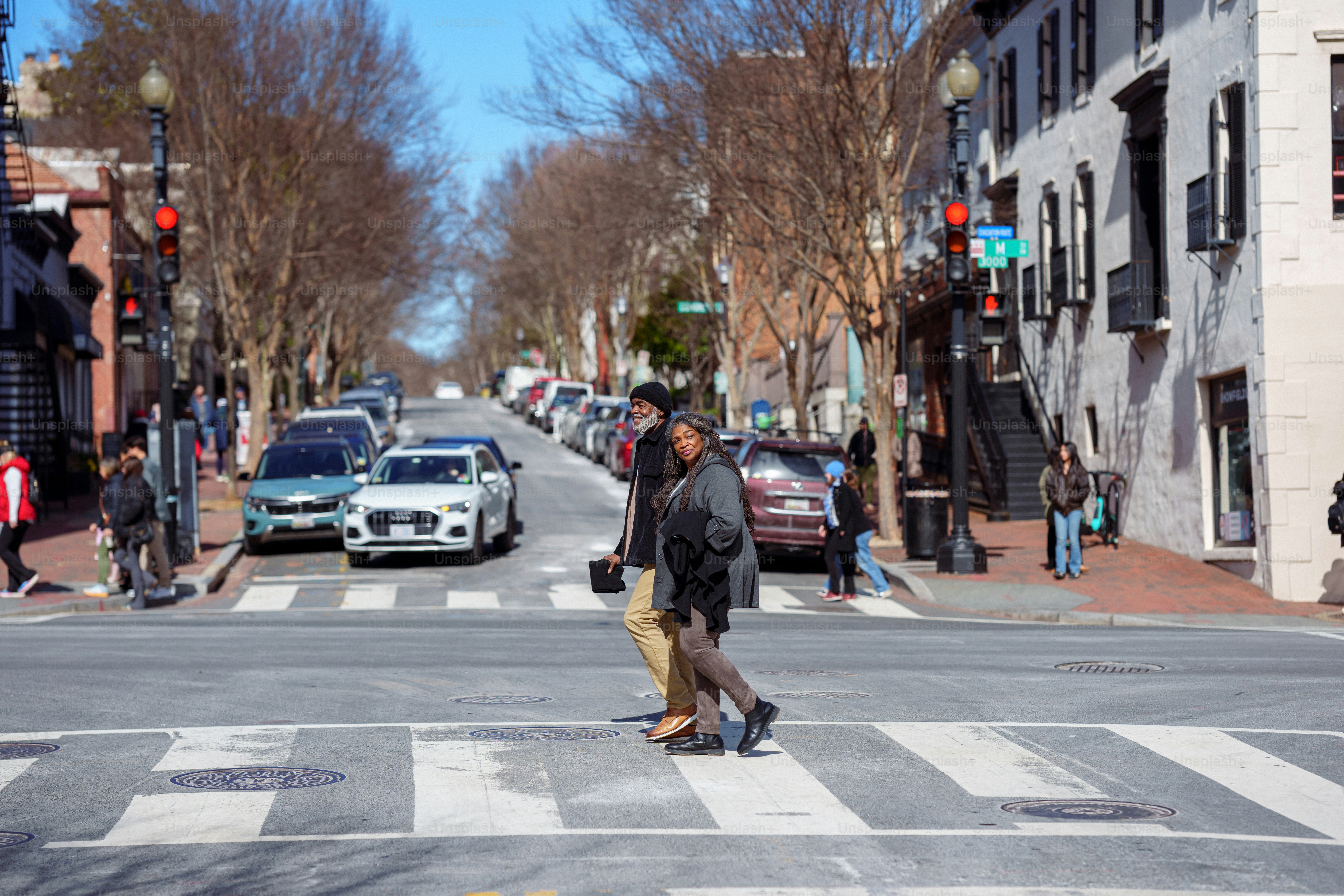 An active and adventurous senior couple of African American descent hold hands and cross a city street at a crosswalk while spending a relaxing winter weekend exploring Washington DC.