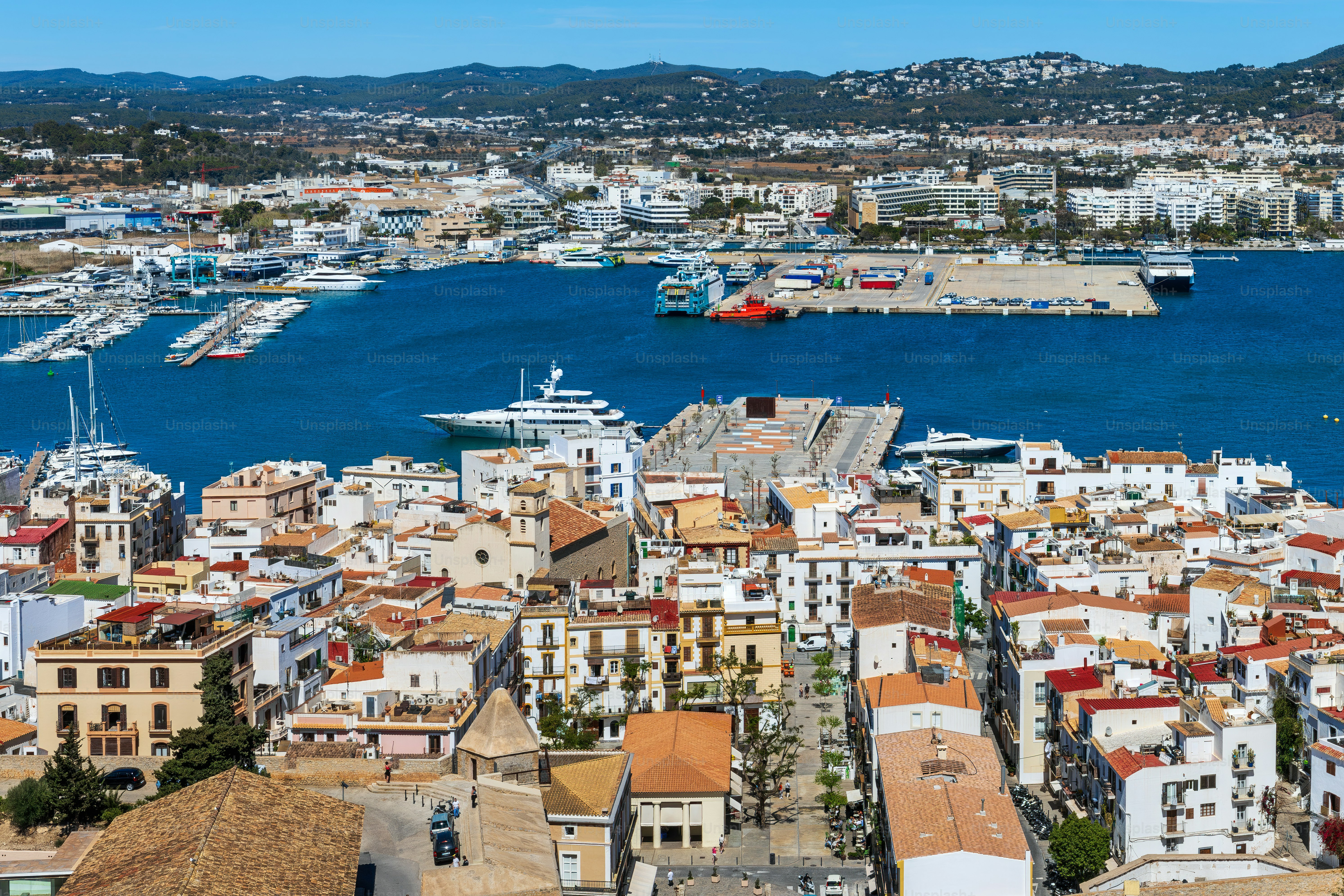 View from above on the white buildings with red and orange roofs and the port of Eivissa, Ibiza, Spain.