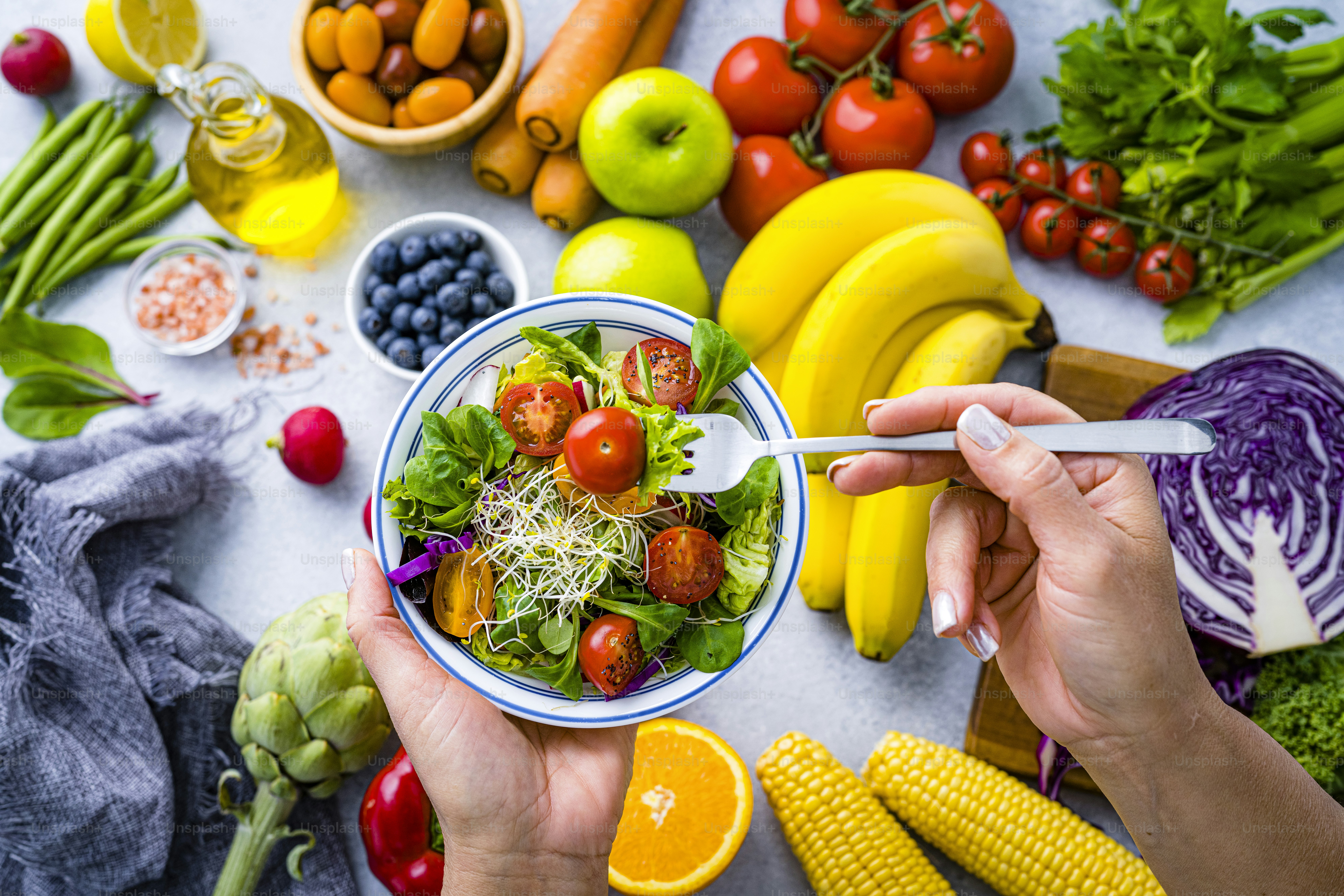 Woman eating fresh rainbow colored salad. Multicolored fruits and vegetables background. Healthy eating and dieting concept. High resolution 42Mp studio digital capture taken with SONY A7rII and Zeiss Batis 40mm F2.0 CF lens
