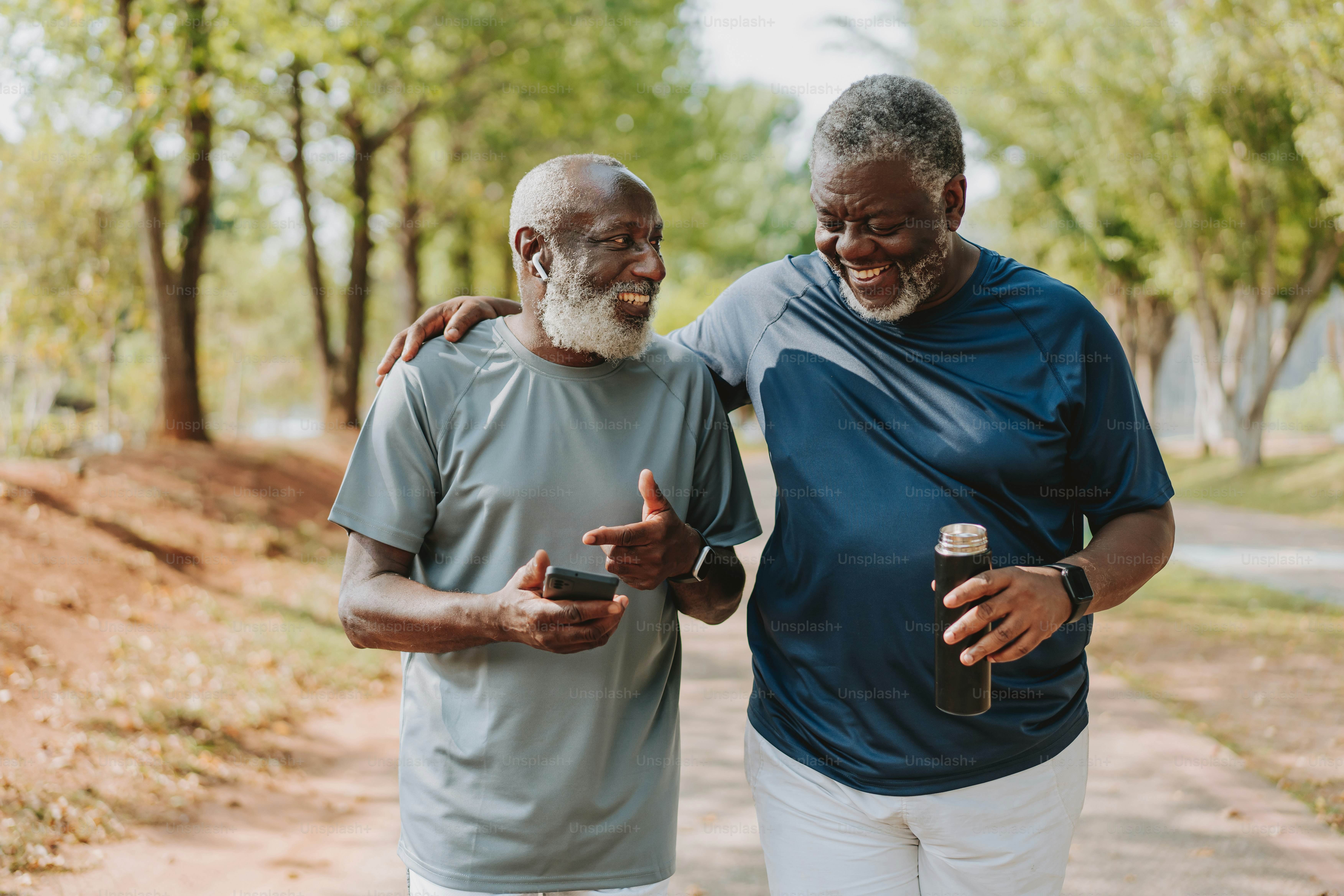 Two black senior friends walking together in public park