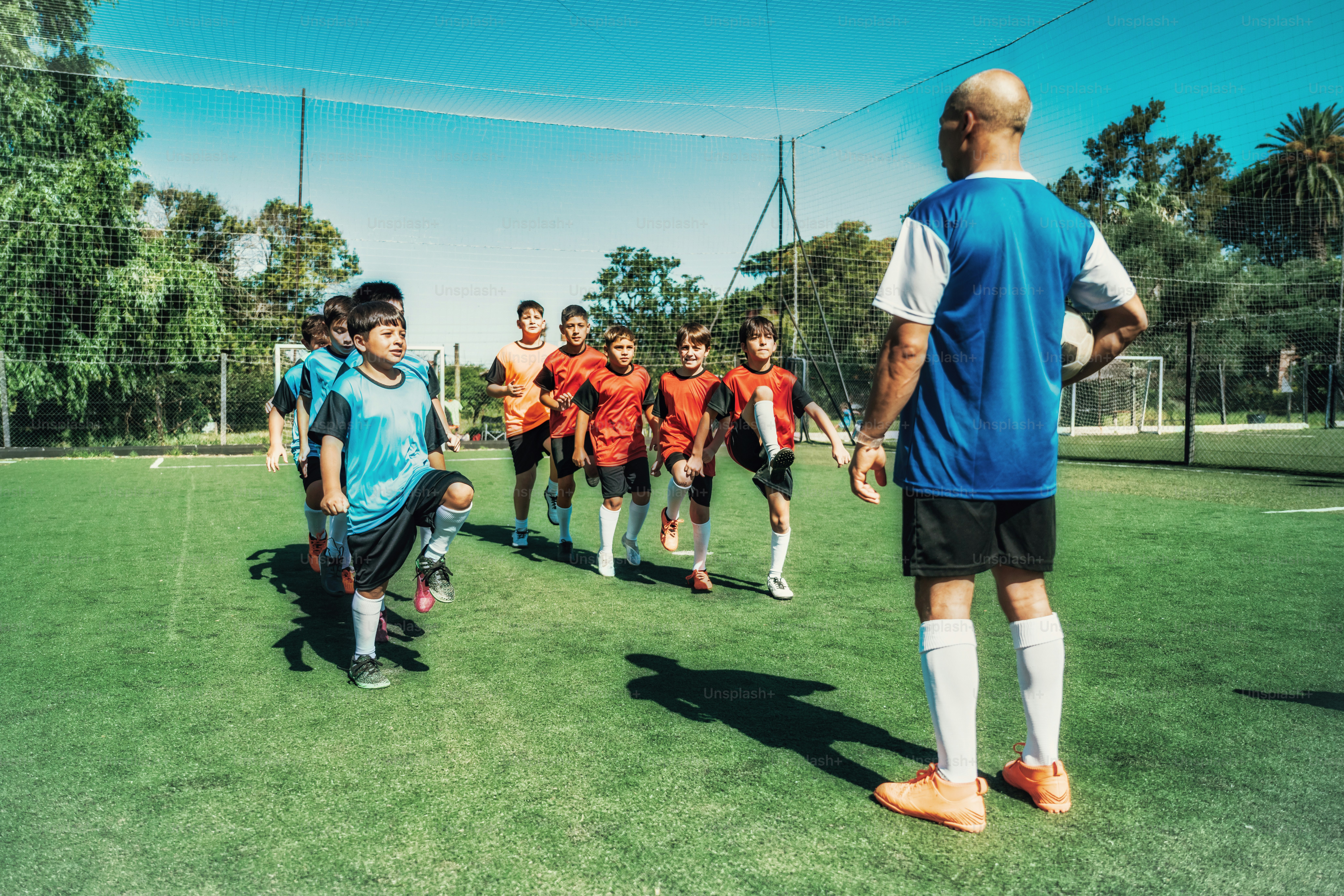 Entrenador de adultos entrenando a dos equipos de fútbol masculino en el campo de fútbol