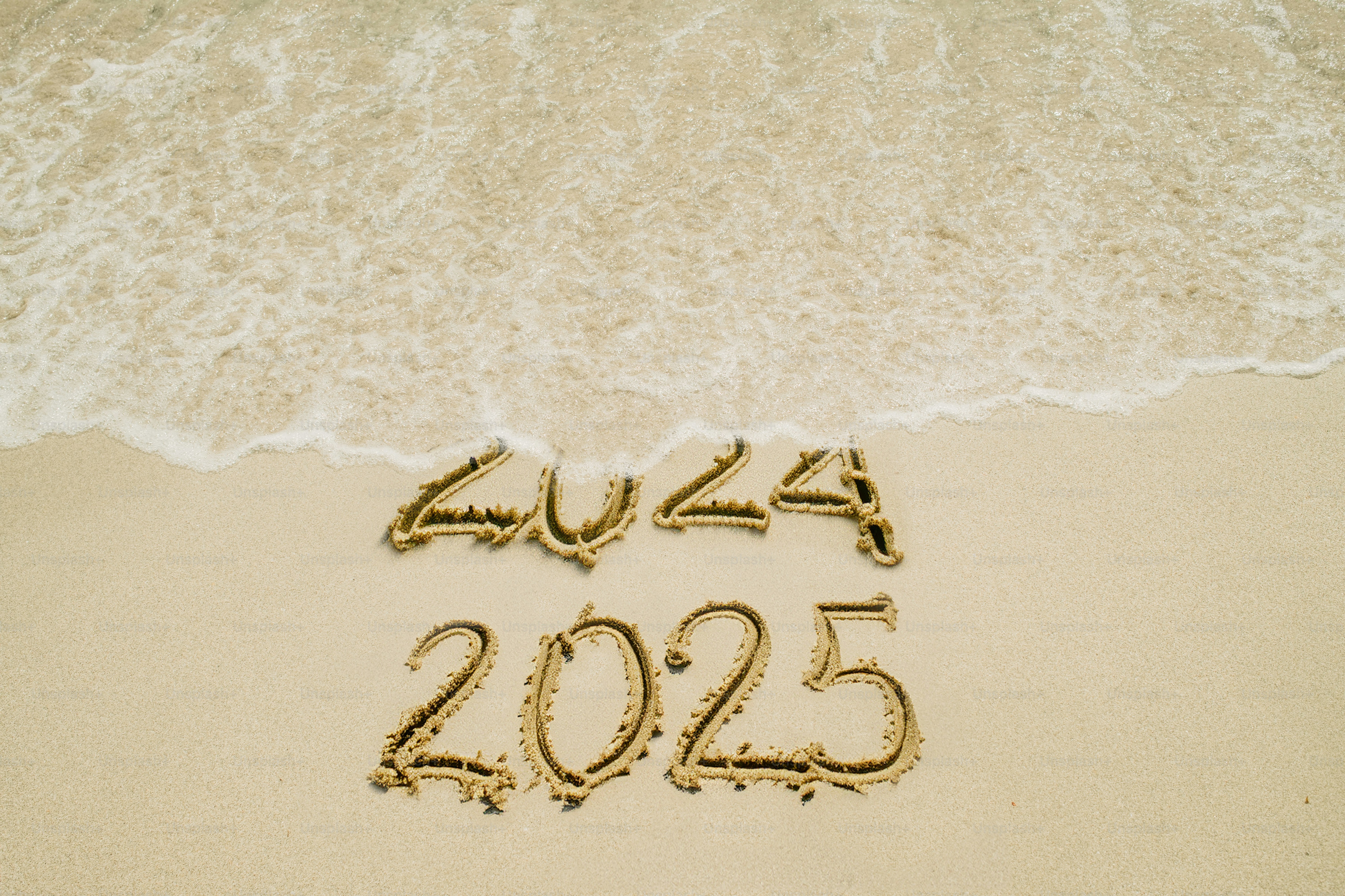 The new year that’s coming is replacing the old year. A wave is cleaning the 2024 text.