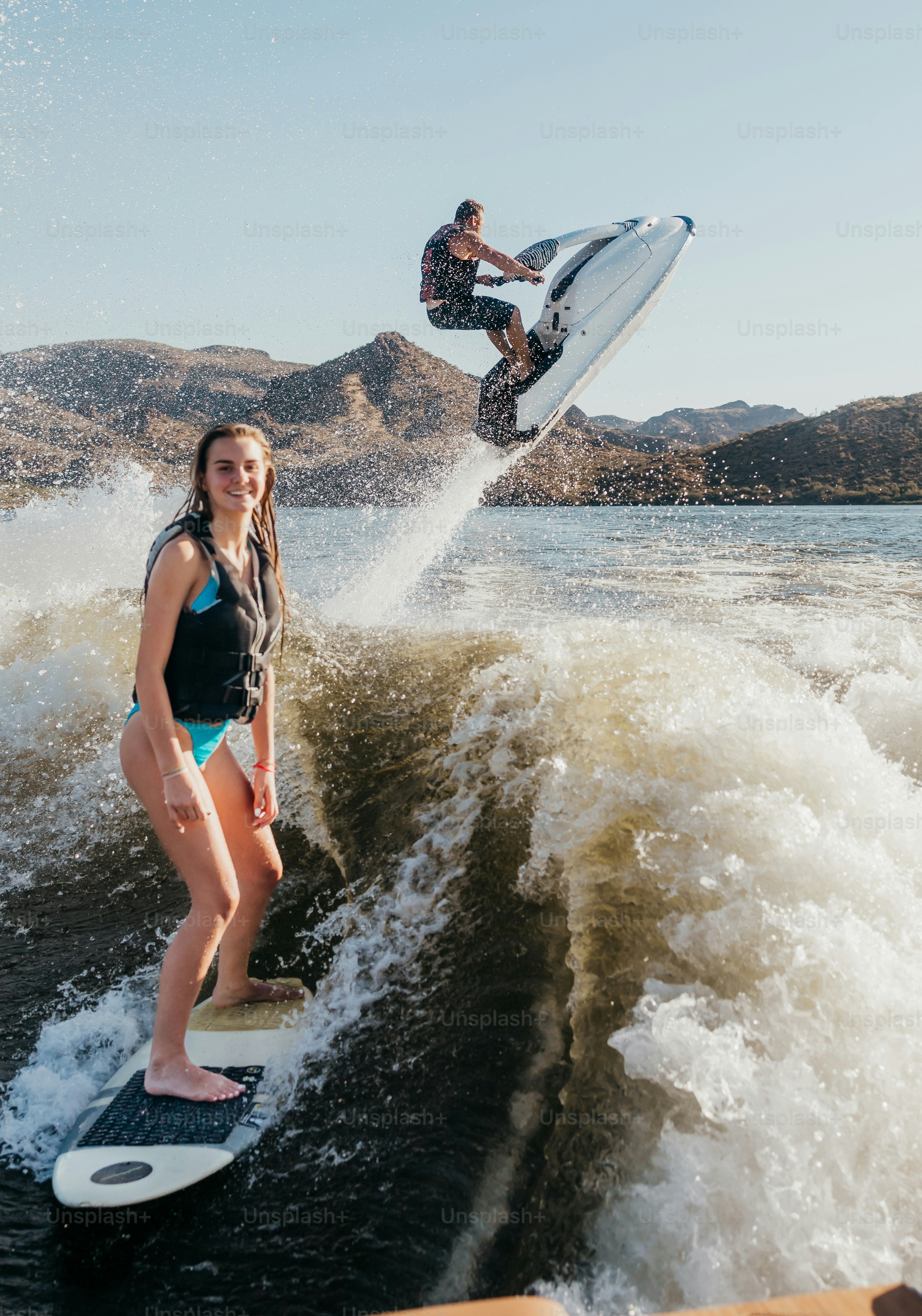 Adolescente fille wakeboards sur le lac, homme mûr prend l’air sur une motomarine derrière elle, lac Saguaro, Arizona