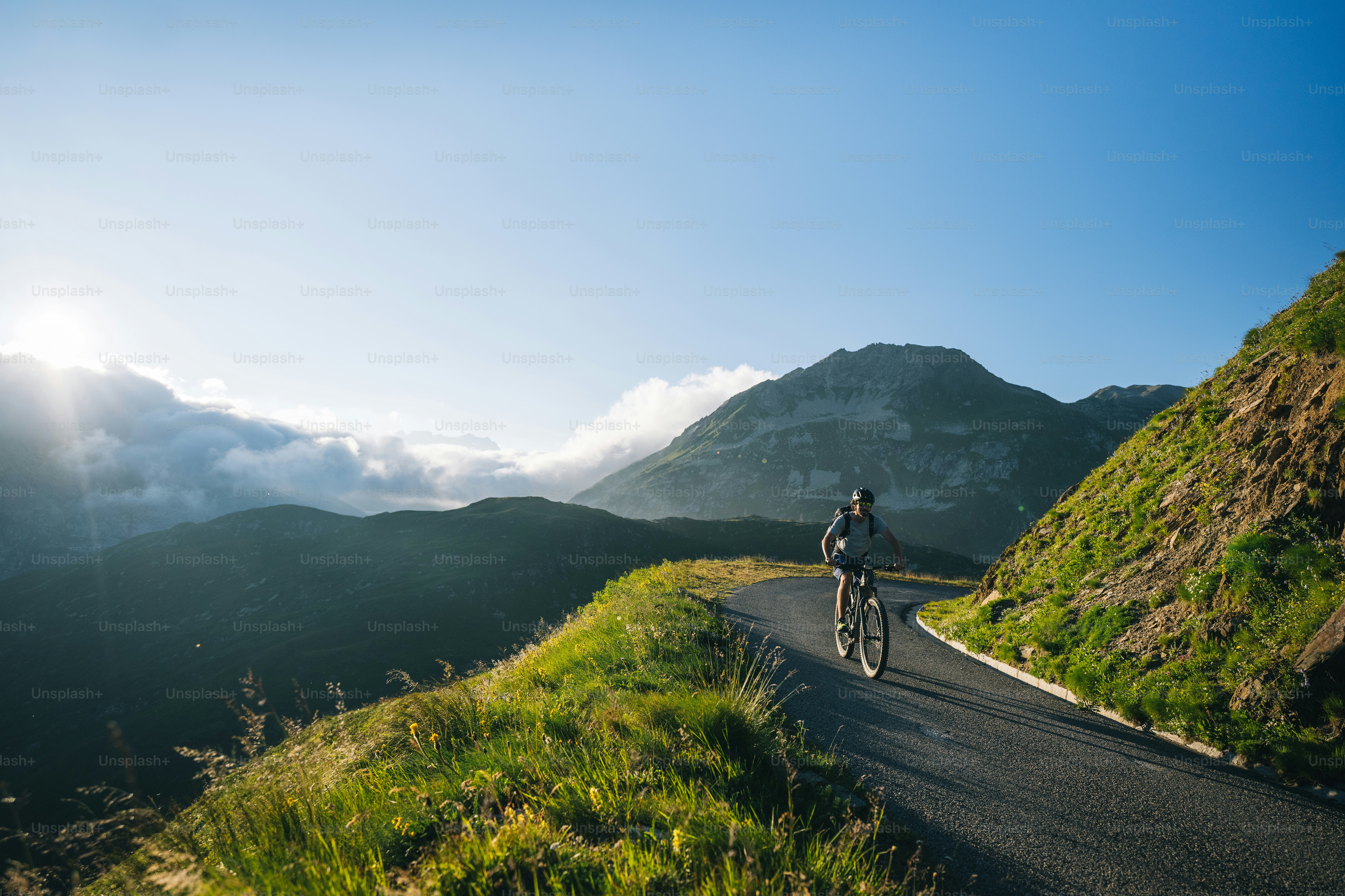 Mountain biker rides mountain road in the morning light, Ticino