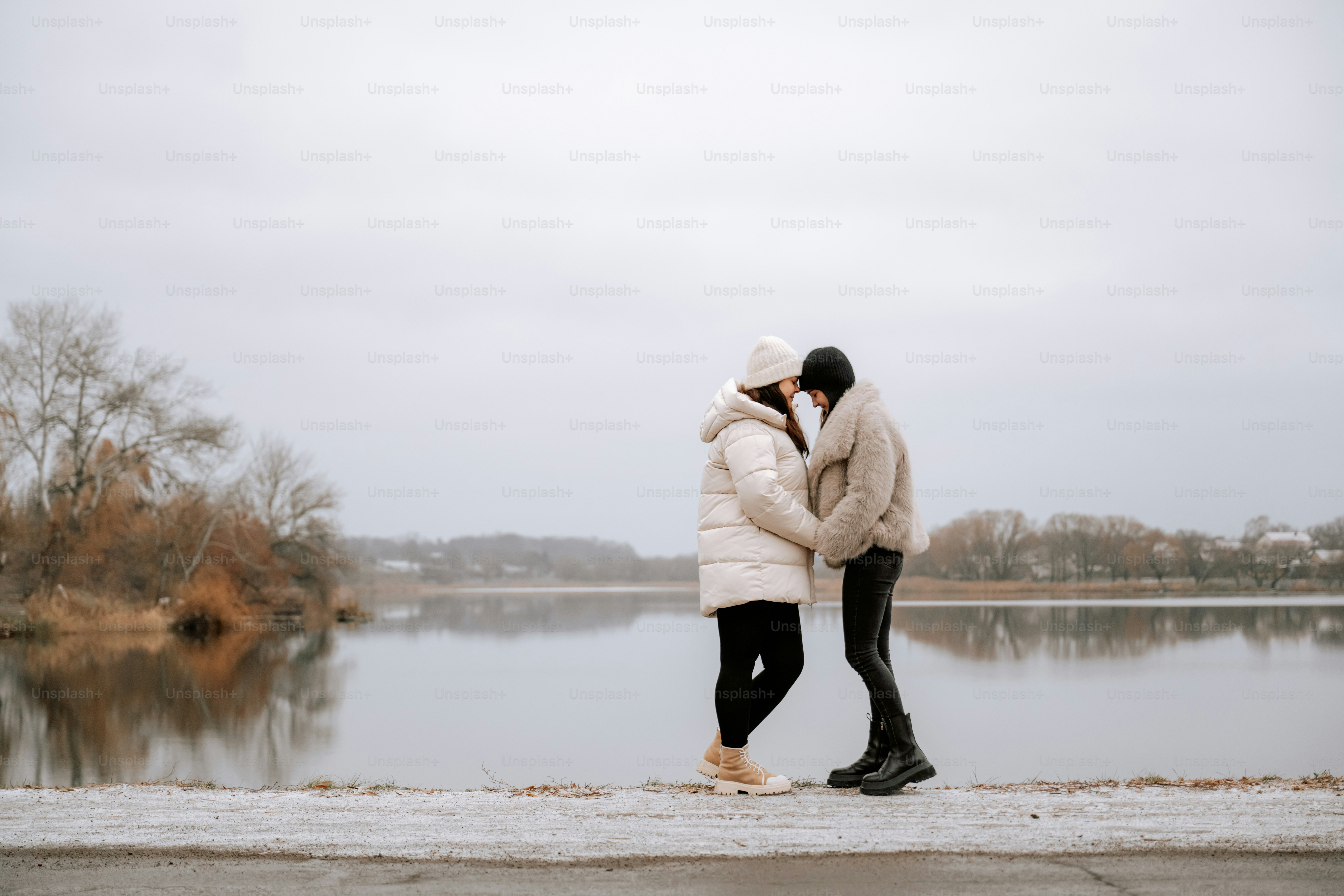 A couple of people standing next to each other near a body of water