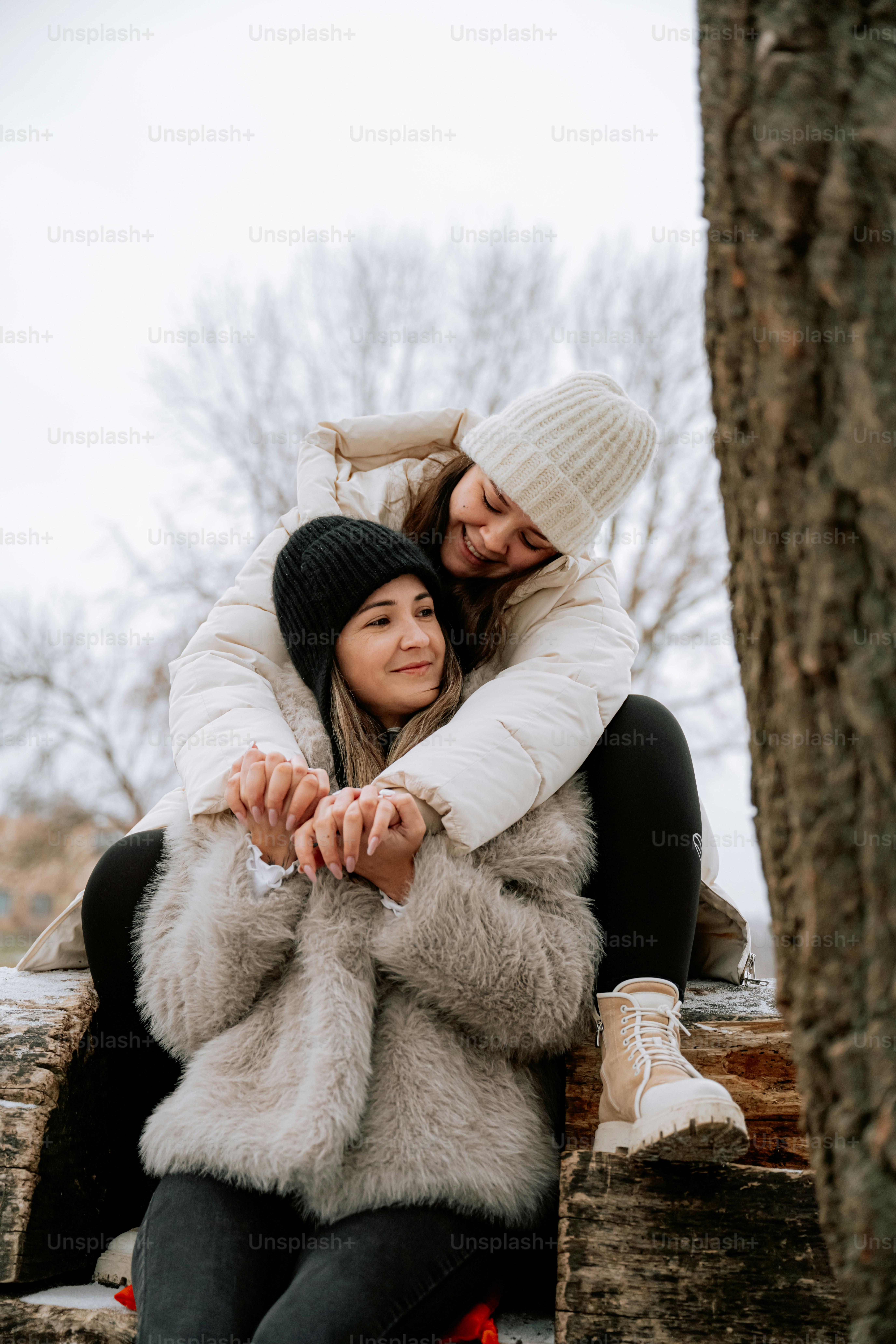 A couple of women sitting next to a tree