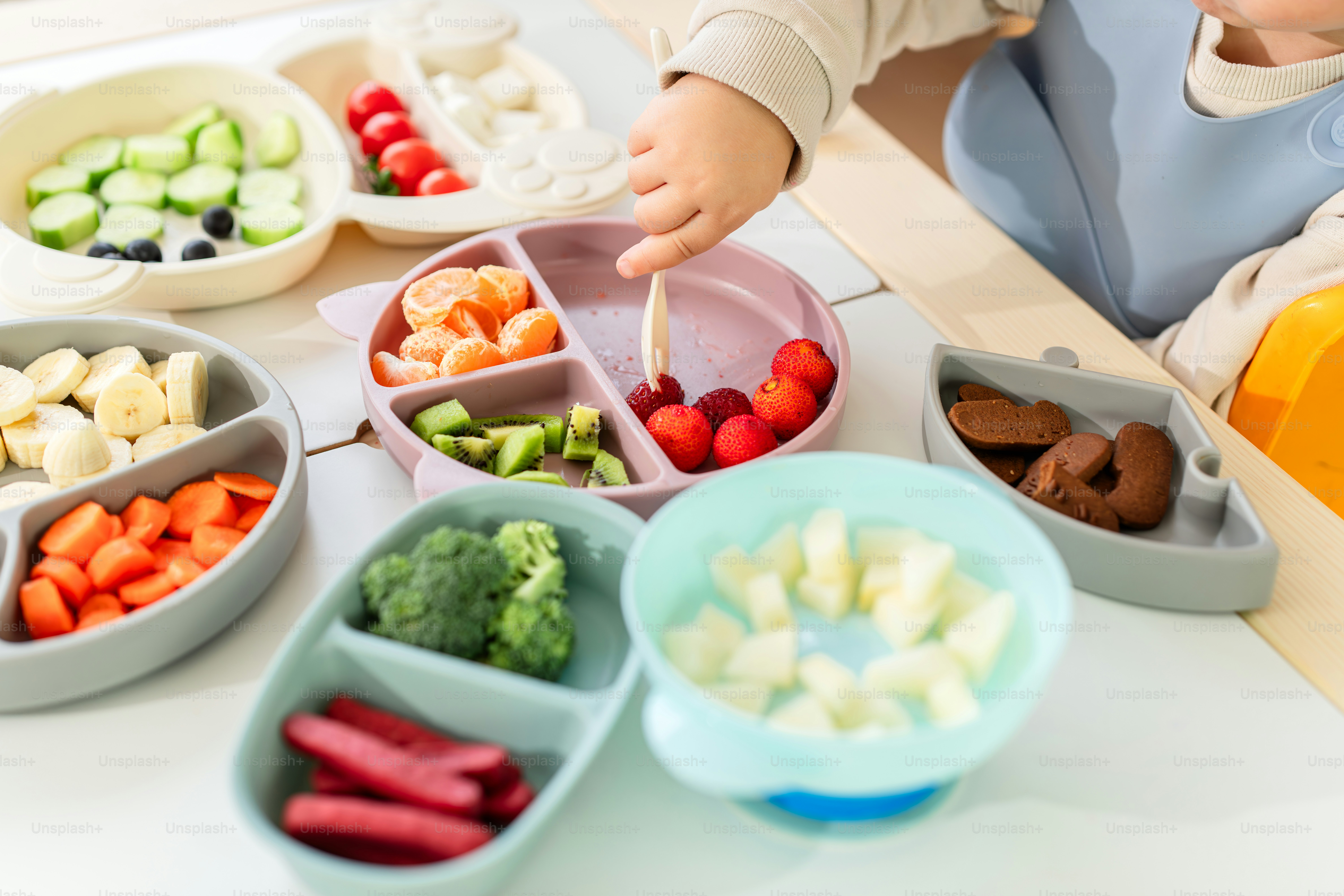 A young child sitting at a table with bowls of food
