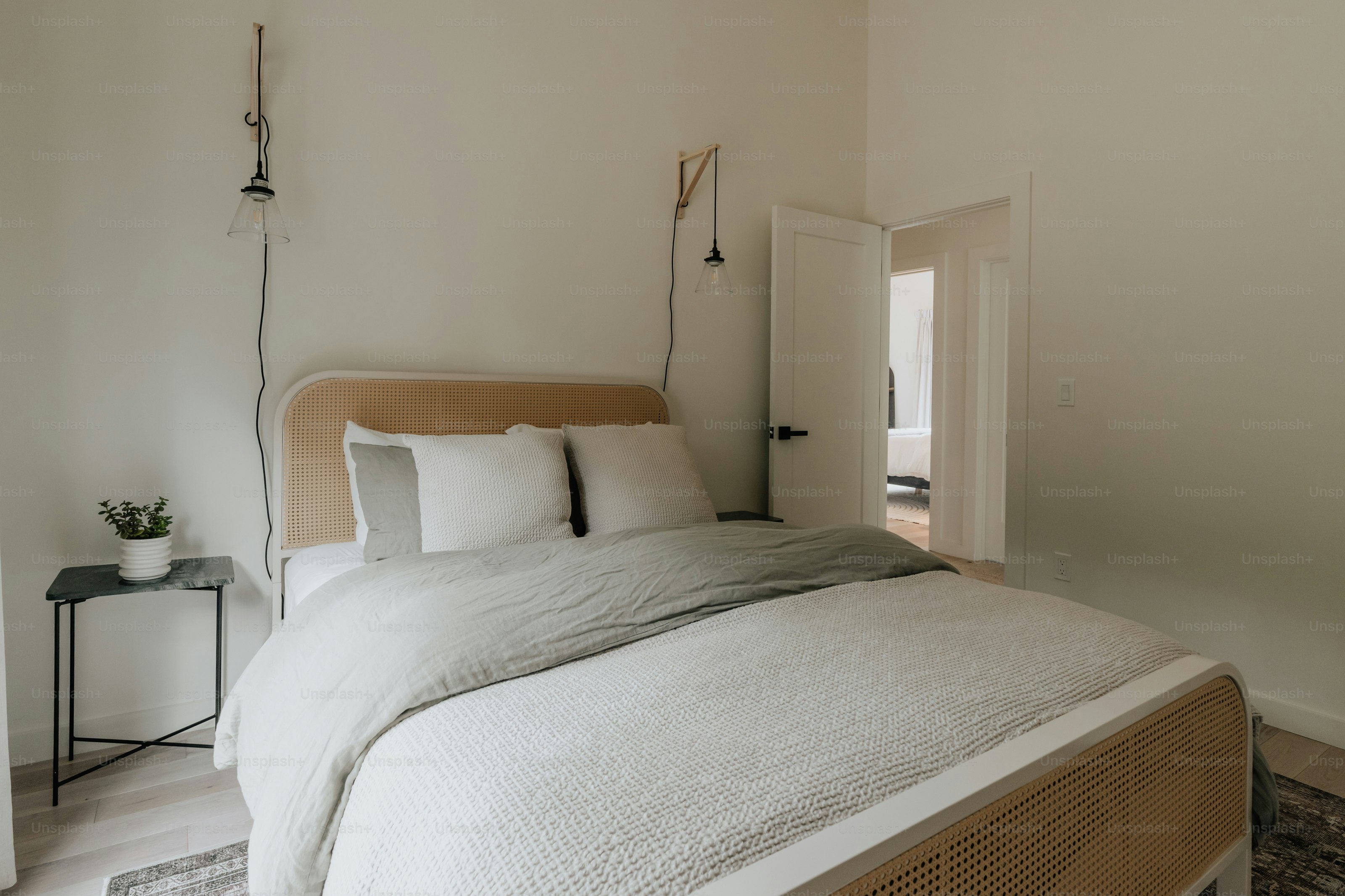 A bed with white sheets and pillows in a room