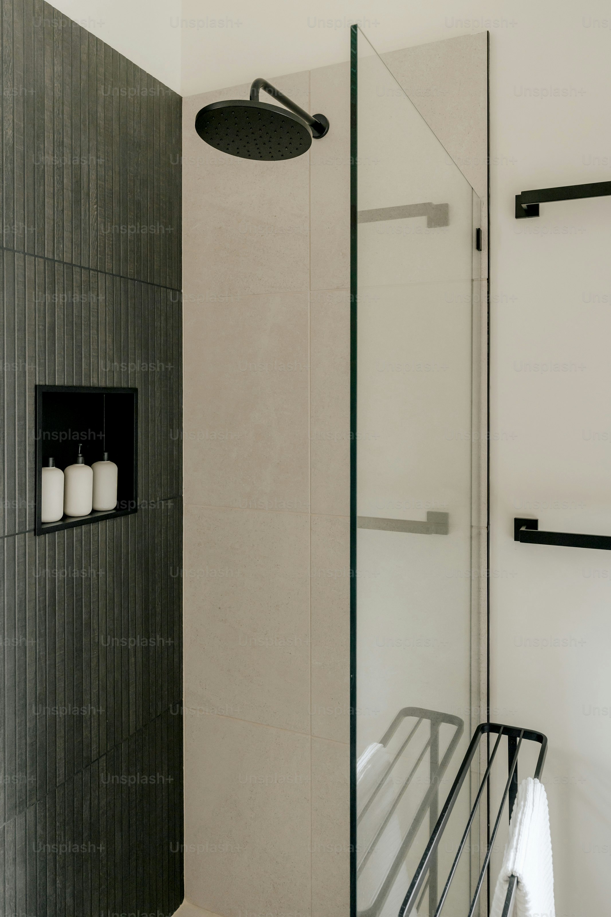 A bathroom with a glass shower door and a towel rack