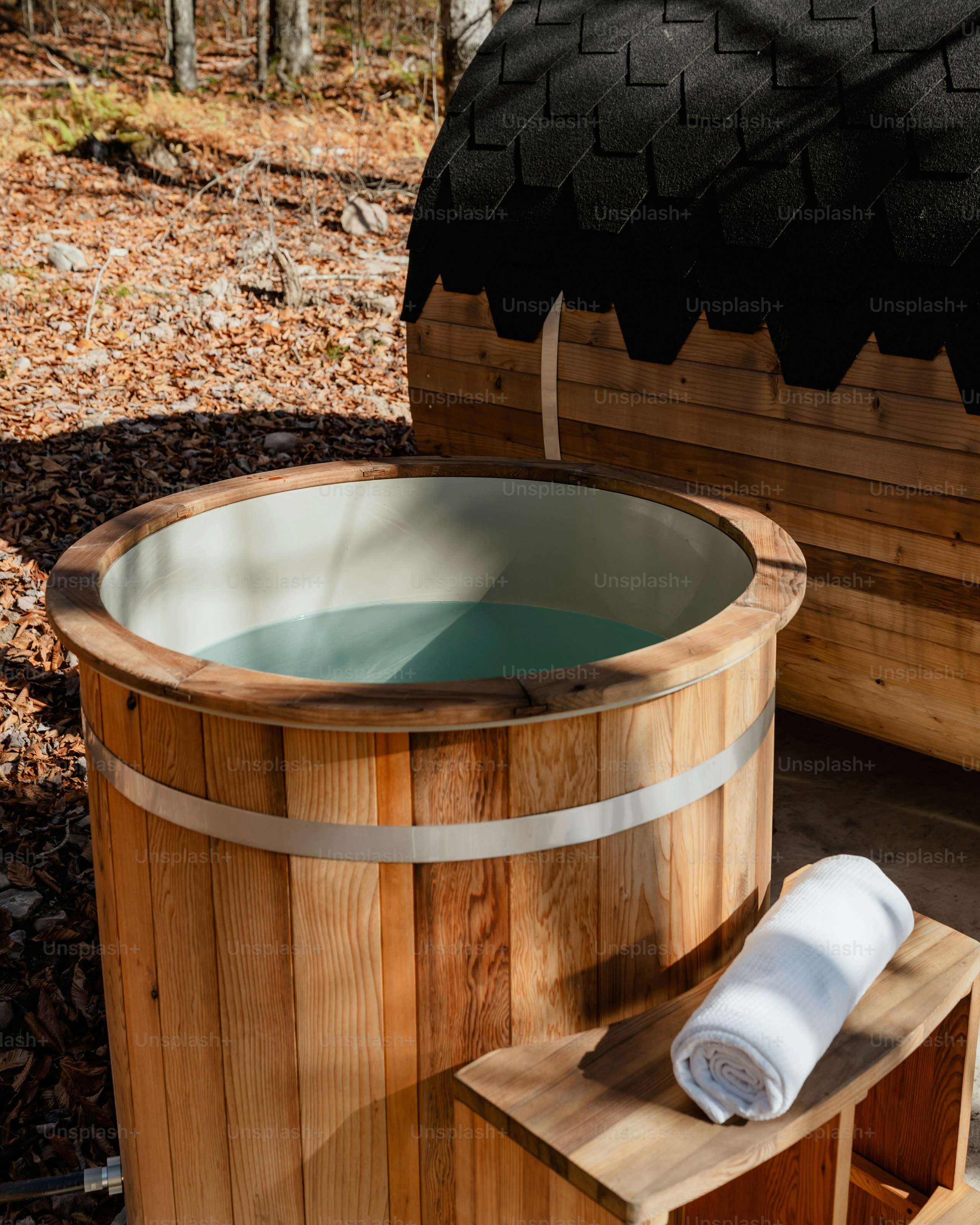 Ein hölzerner Whirlpool sitzt neben einem Baum