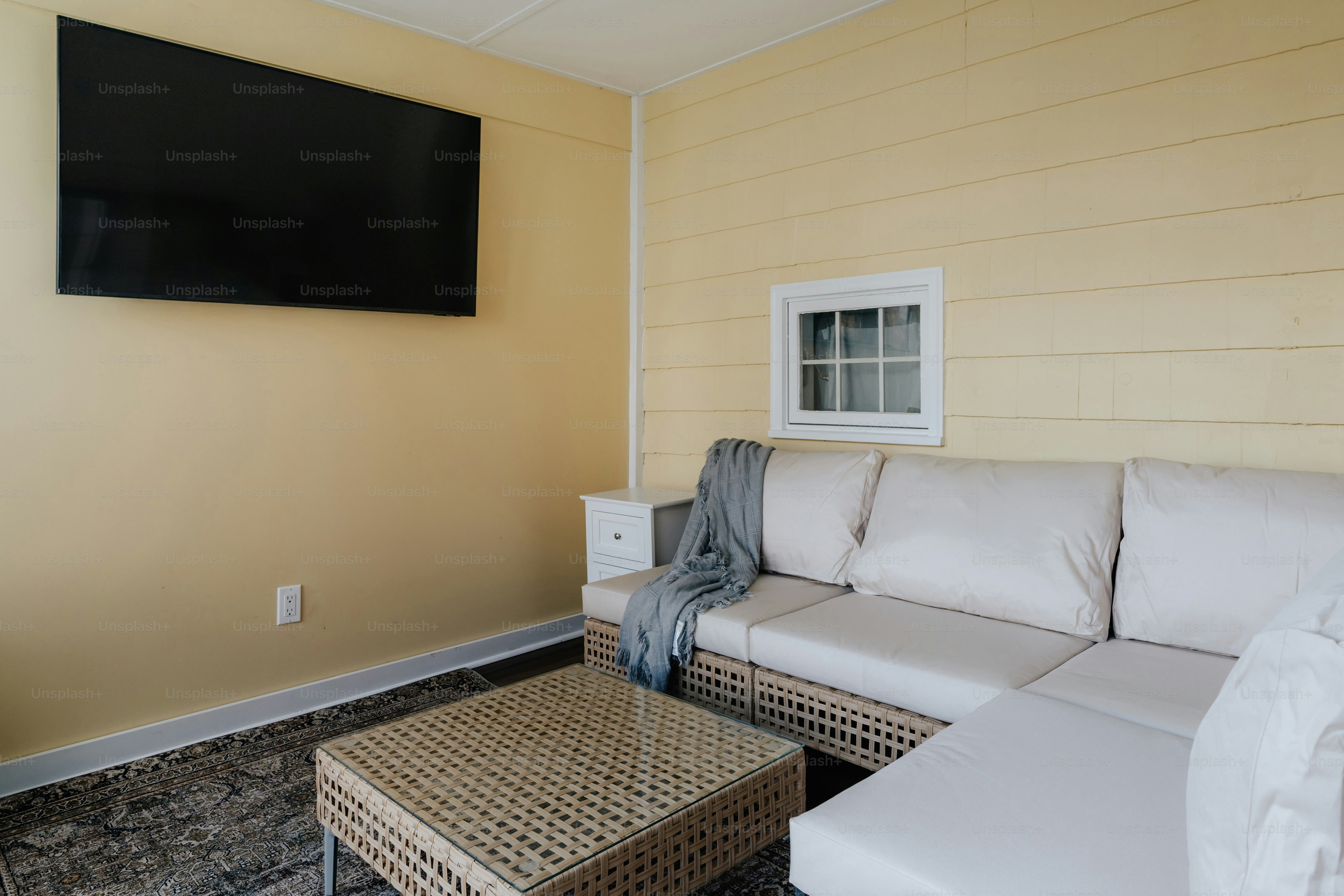 Ein Wohnzimmer mit einer weißen Couch und einem Flachbildfernseher