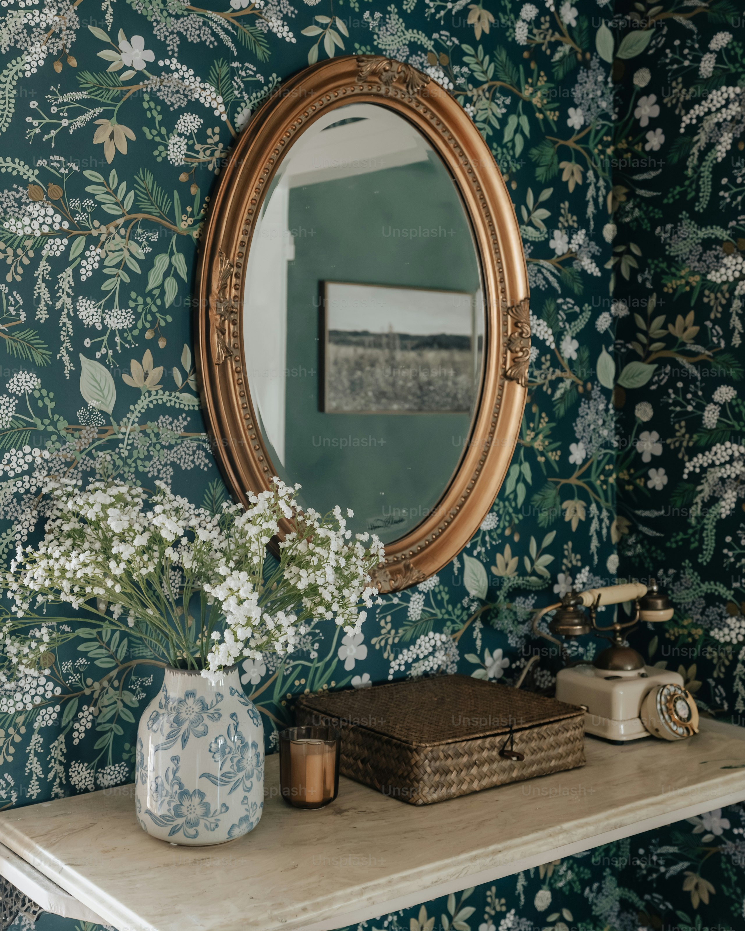 Un espejo encima de una estantería junto a un jarrón de flores