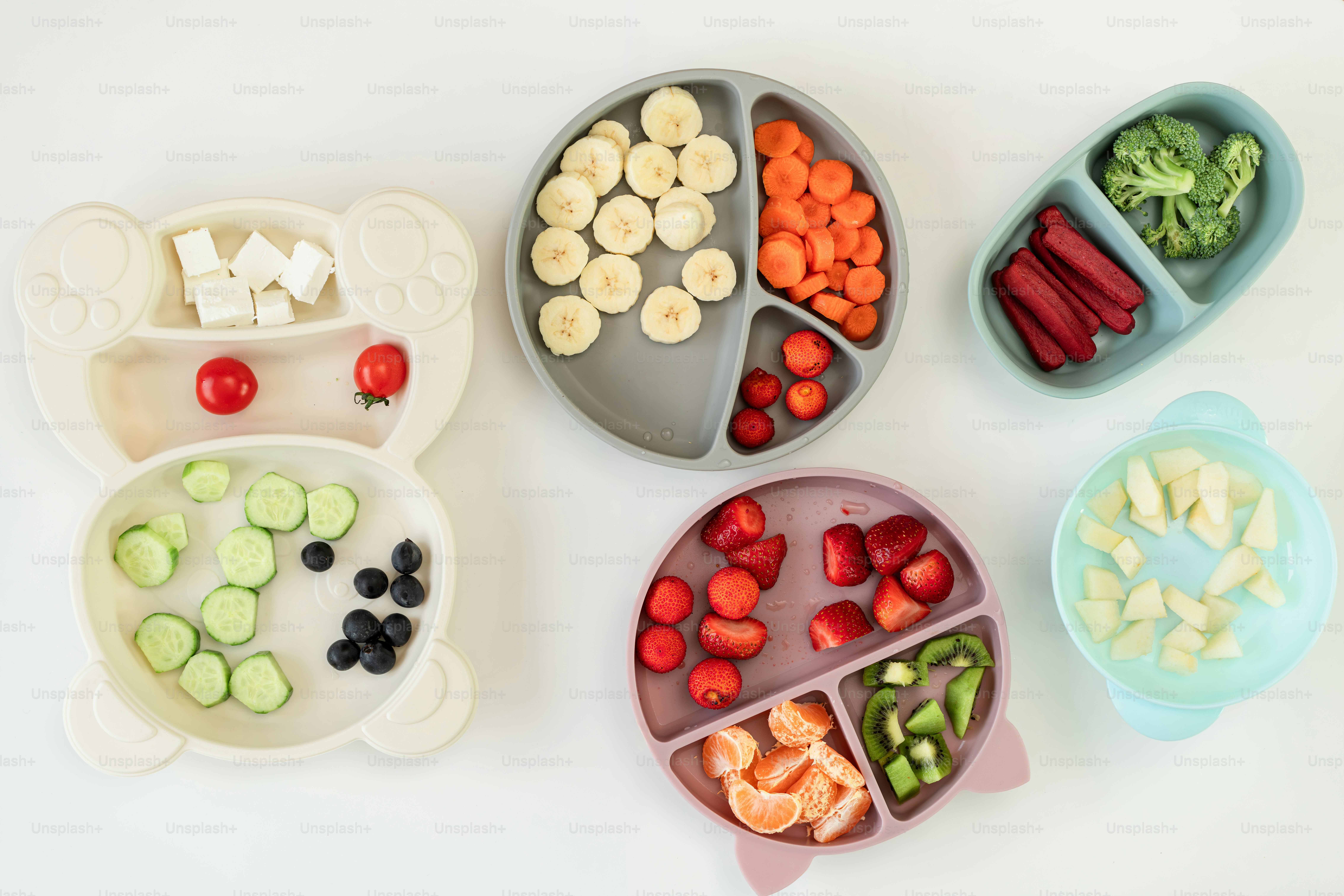 A white table topped with four trays filled with food
