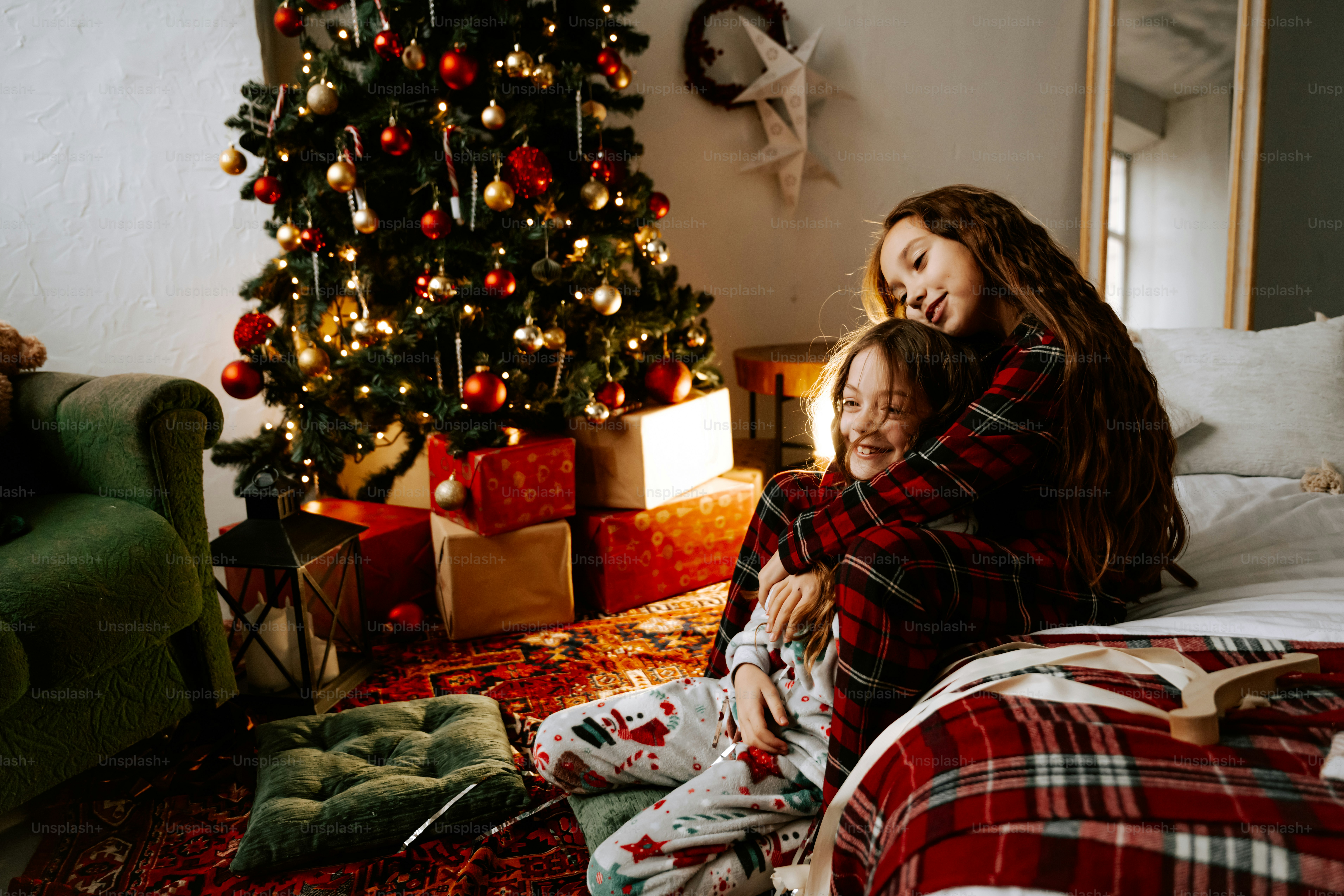 Deux filles assises sur un lit devant un sapin de Noël