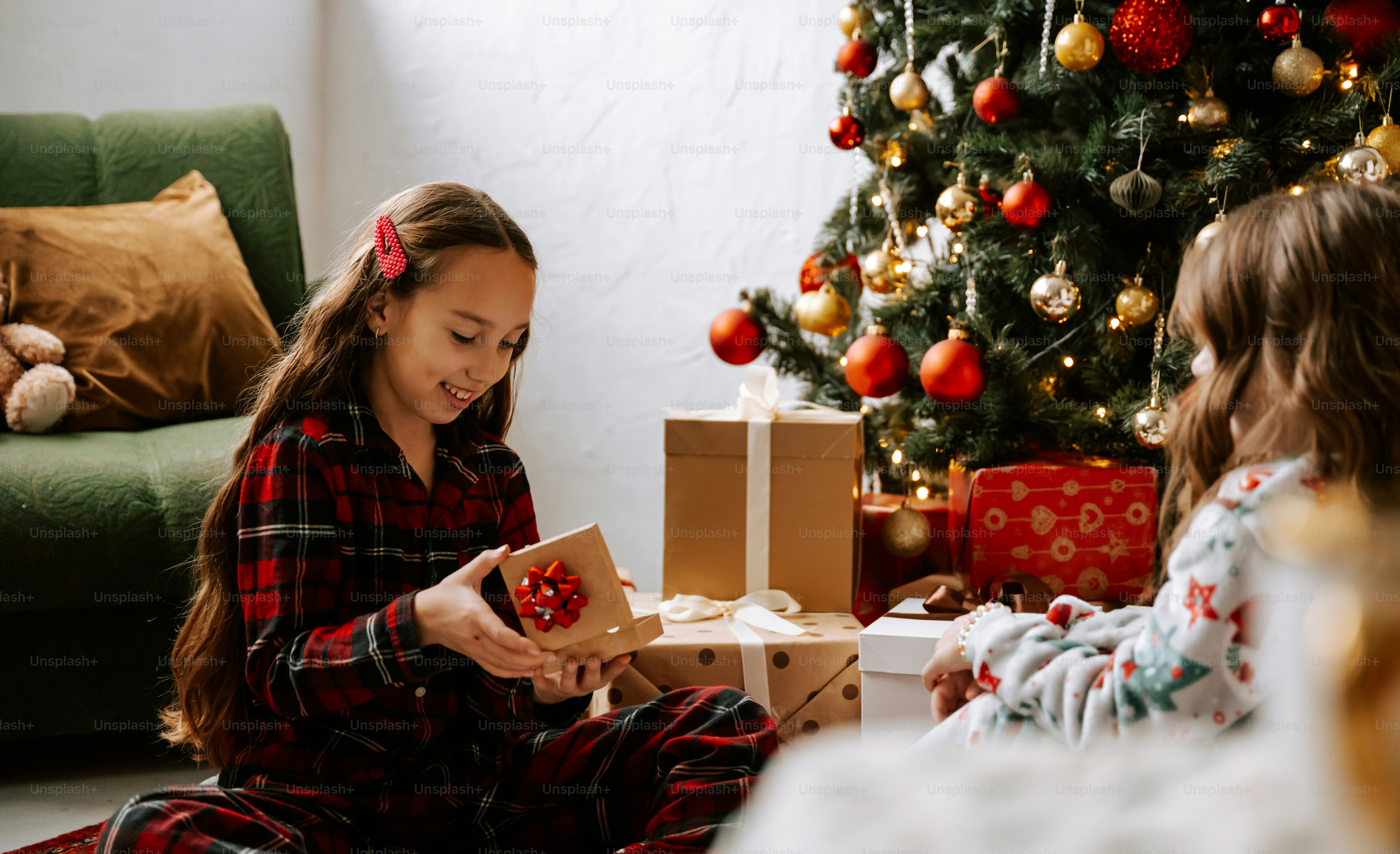 Two girls sitting on the floor near a christmas tree