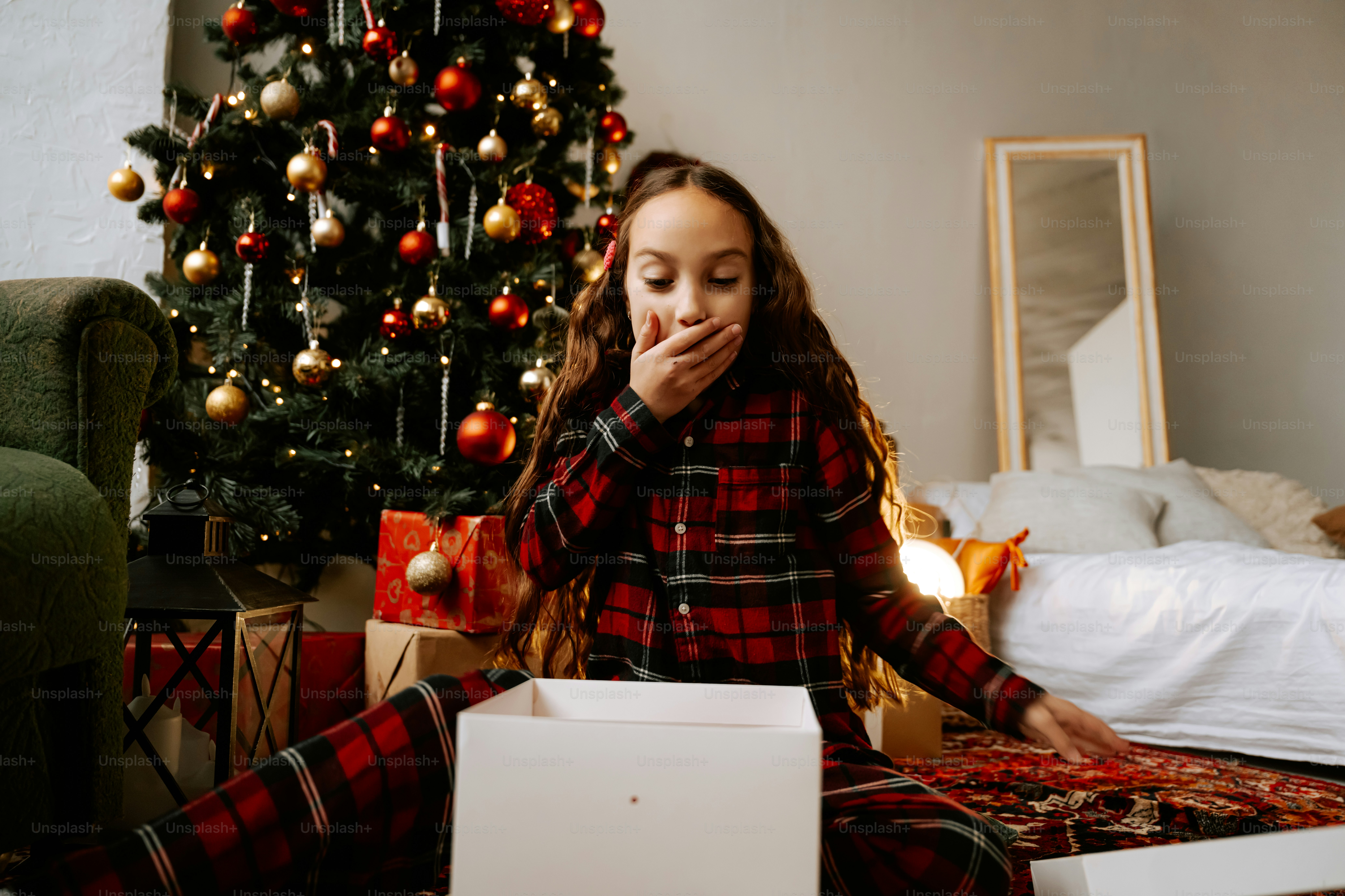 A girl sitting on the floor in front of a christmas tree
