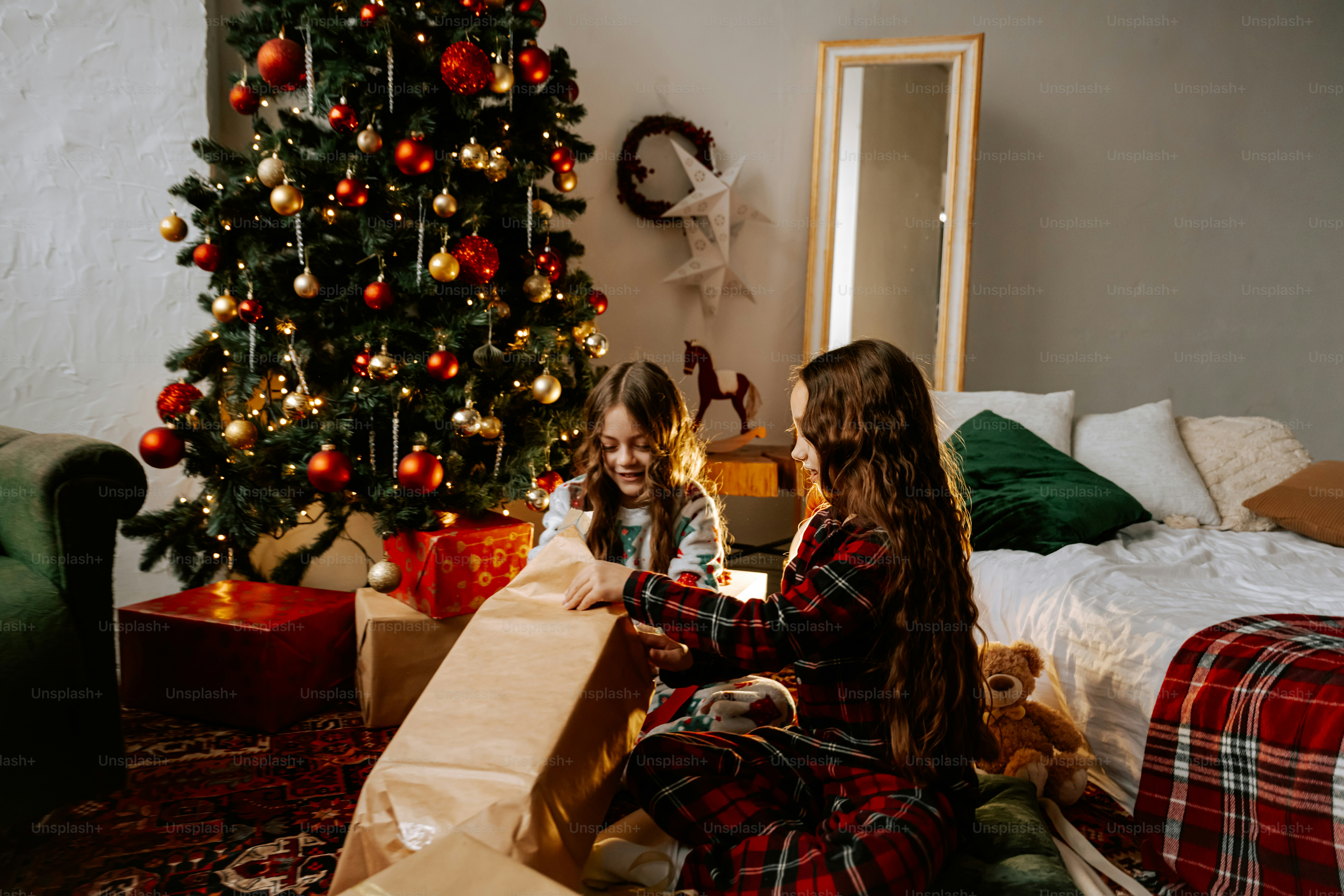 Two girls sitting on the floor in front of a christmas tree