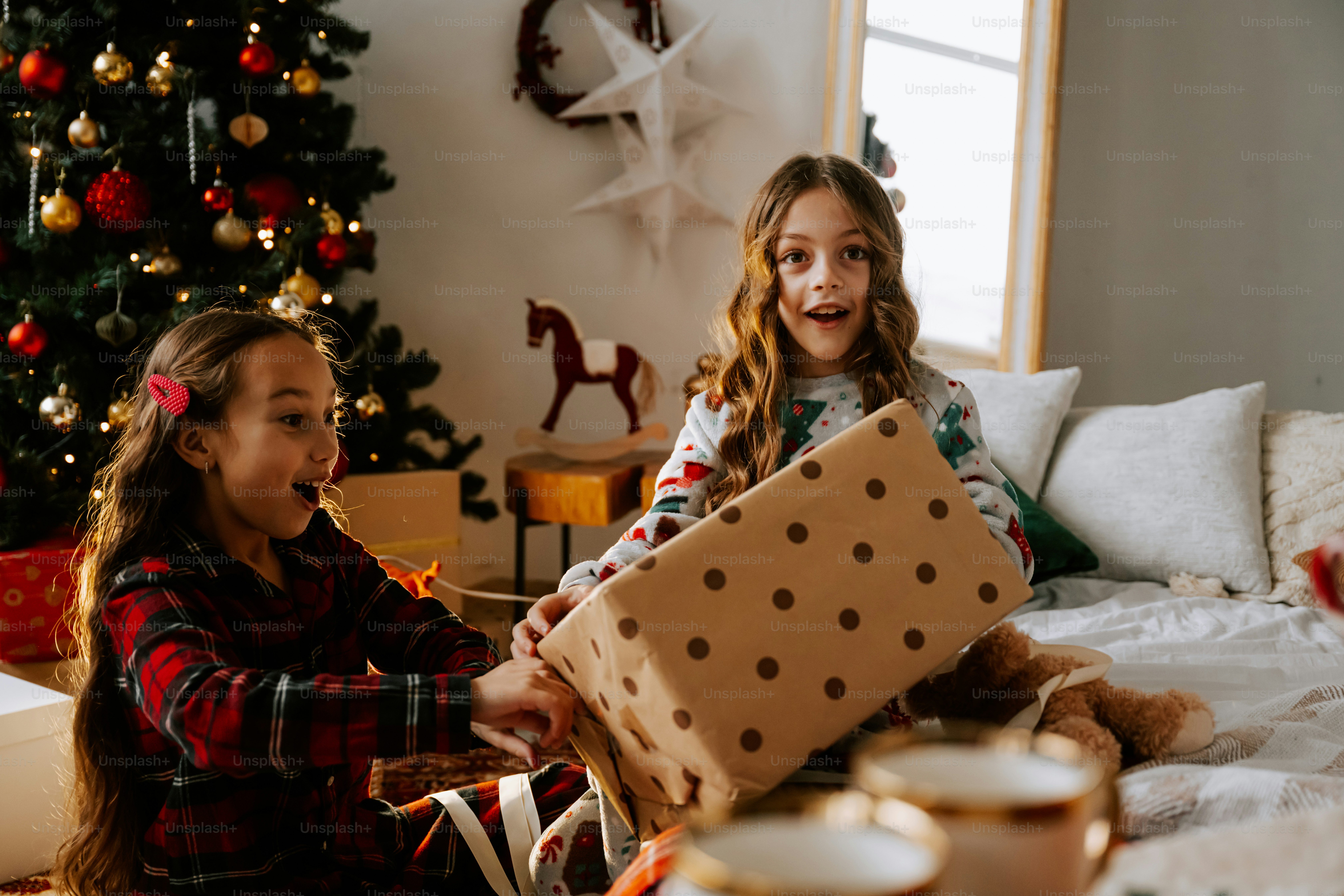 Two little girls sitting on a bed with presents