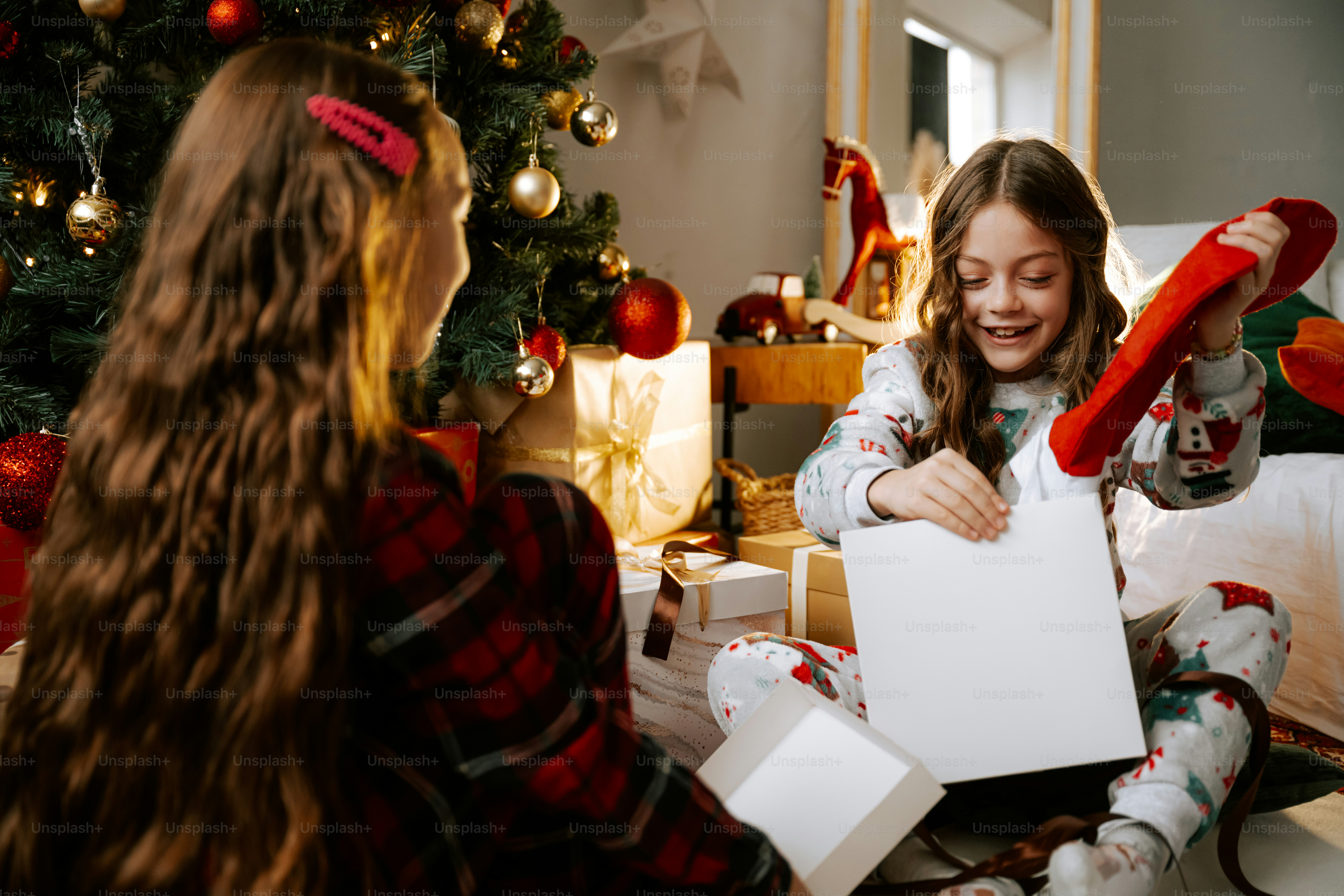 Two girls sitting on the floor near a christmas tree