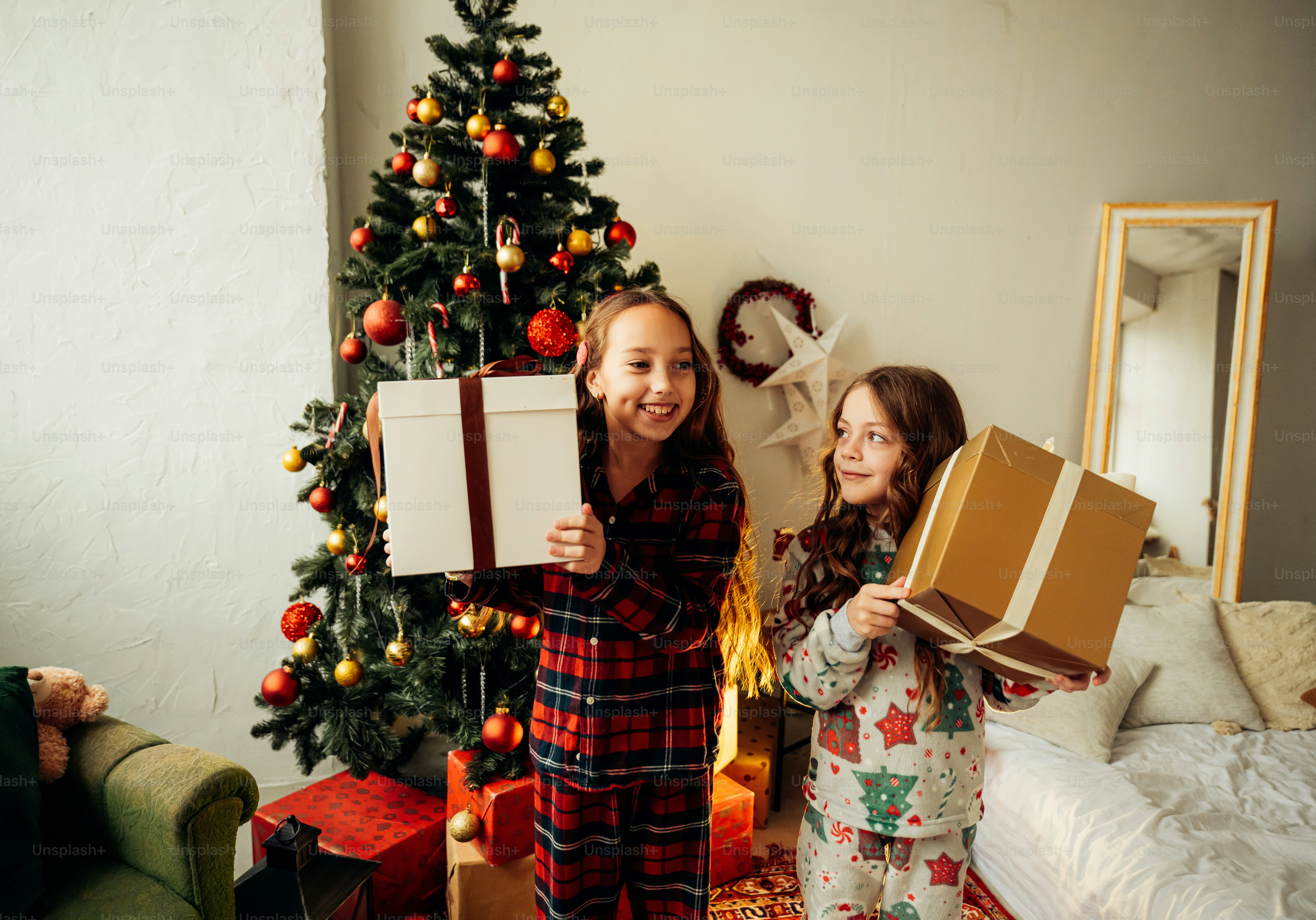 A couple of women standing next to a christmas tree