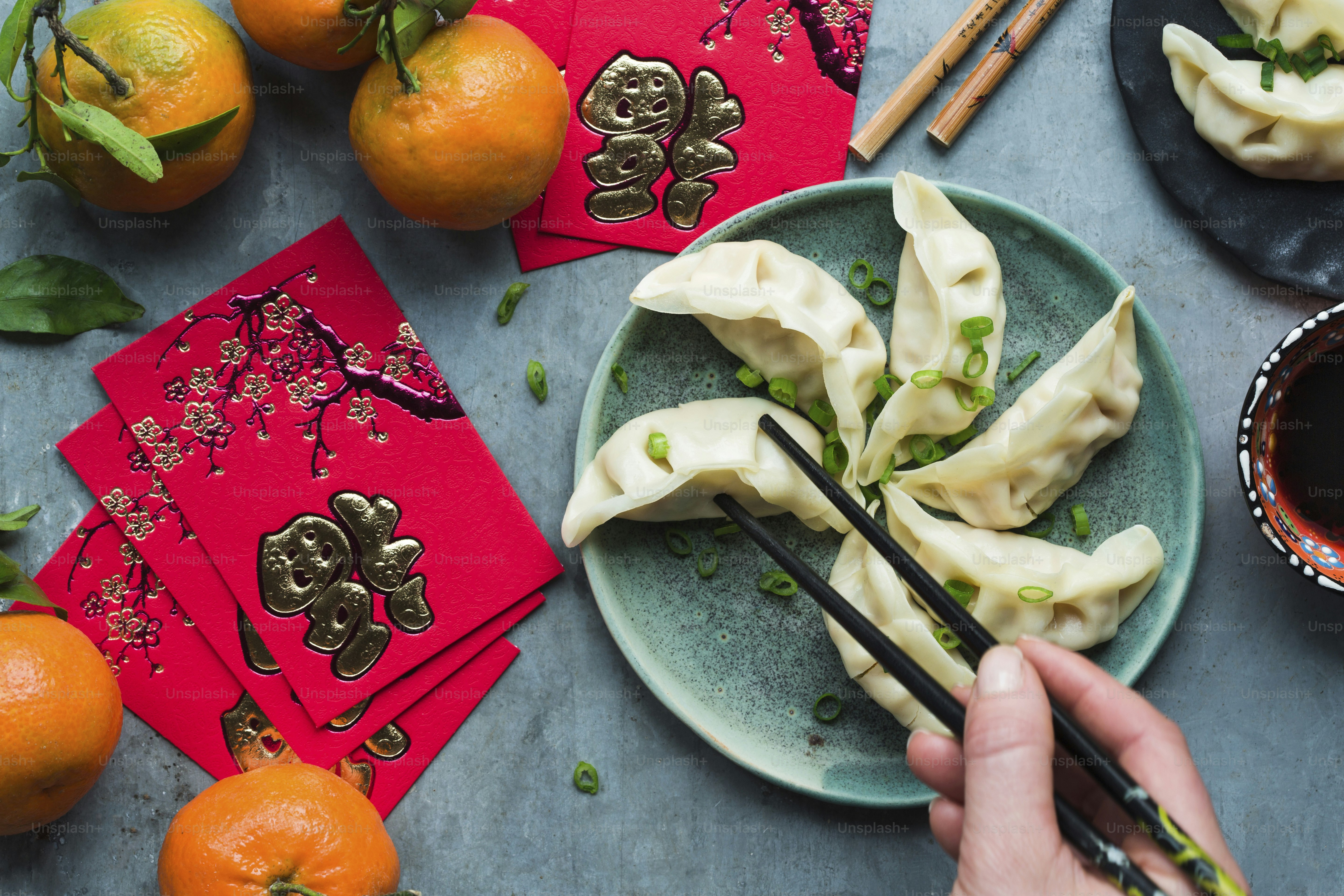 A person holding chopsticks over a plate of dumplings