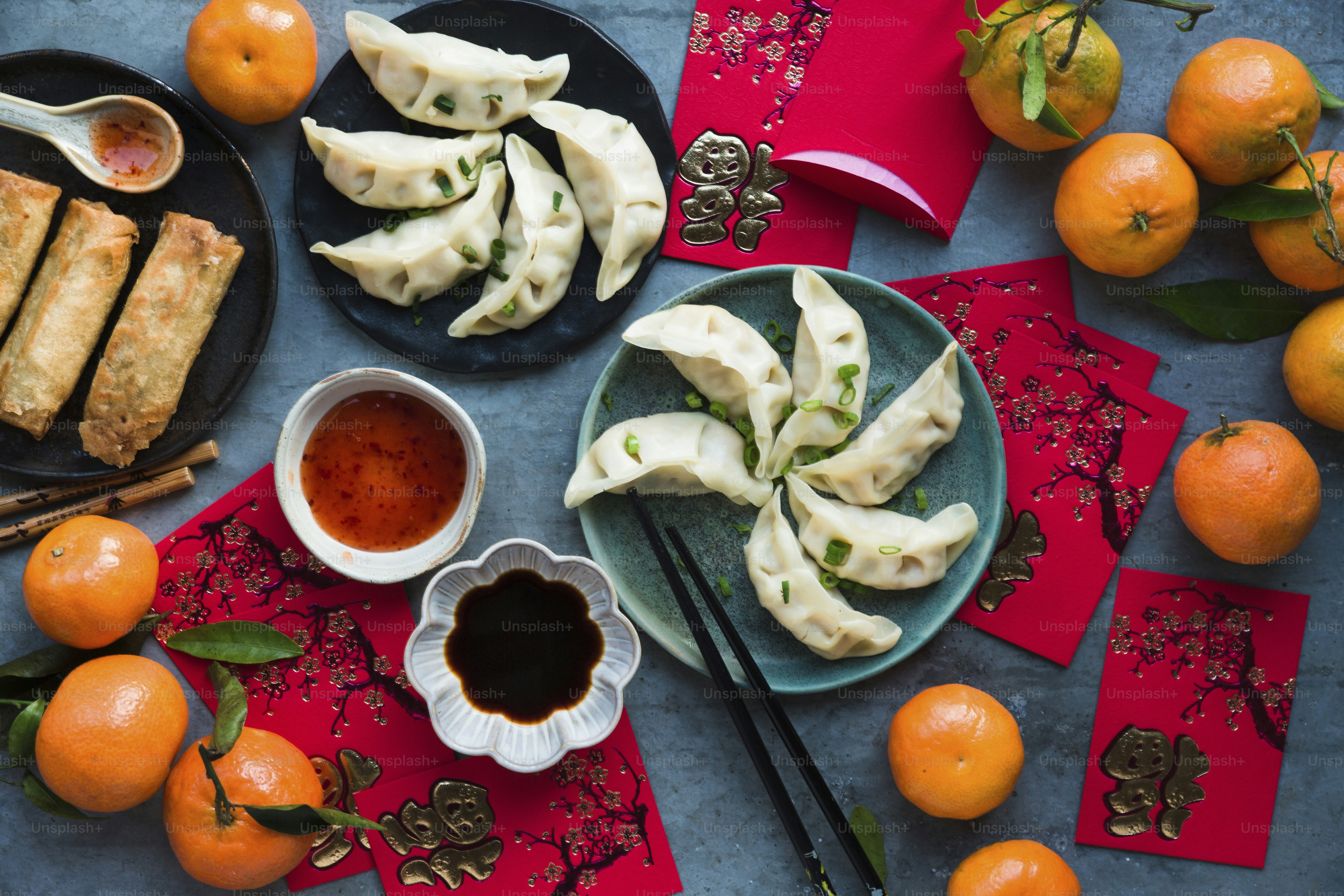 A table topped with plates of food next to oranges