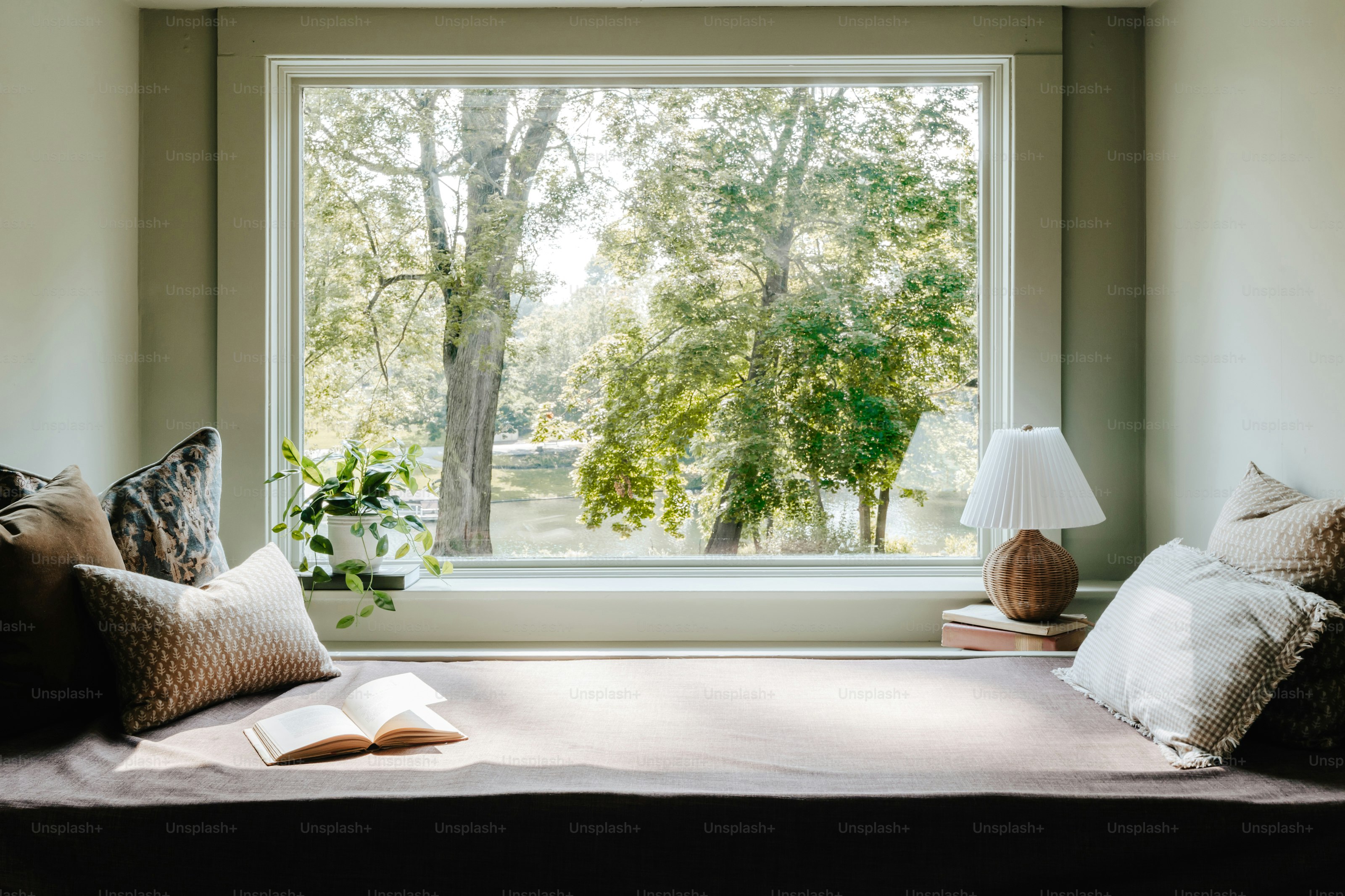 Un letto con cuscini e una lampada davanti a una finestra