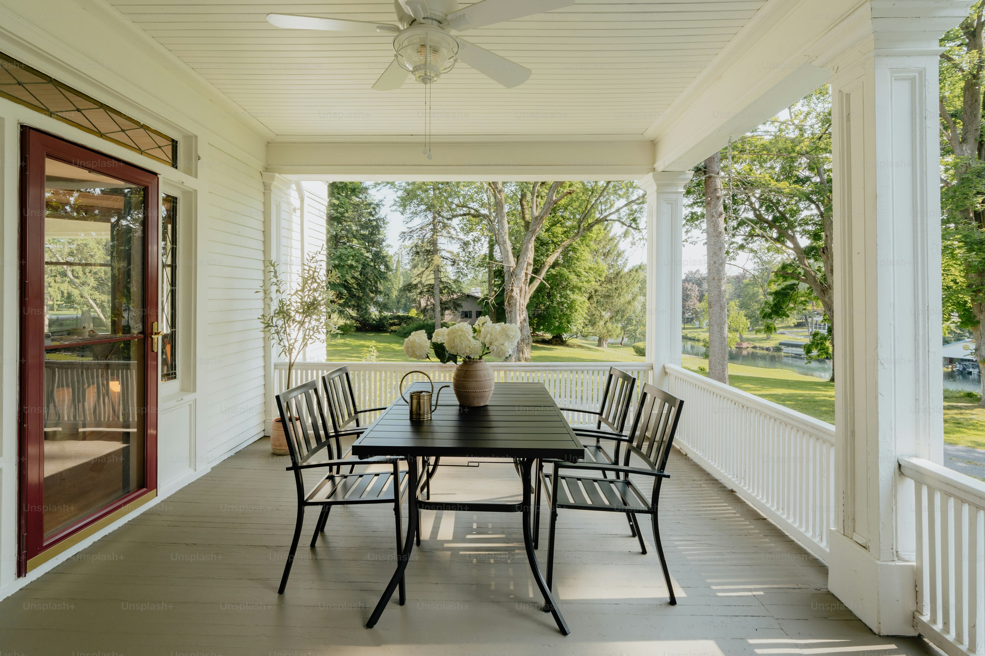 A porch with a table and chairs and a ceiling fan