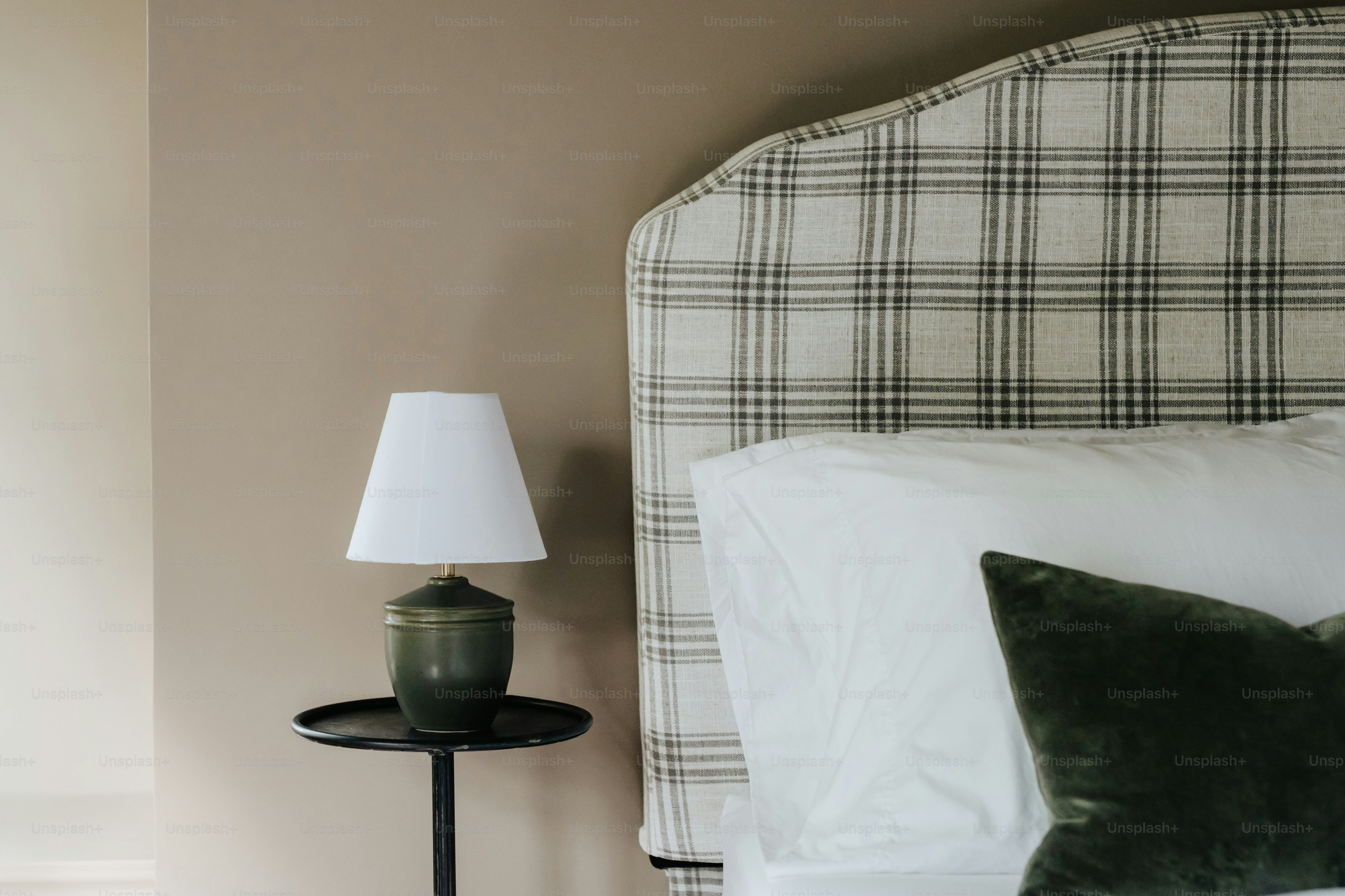 Uma cama com cabeceira xadrez e mesa de cabeceira