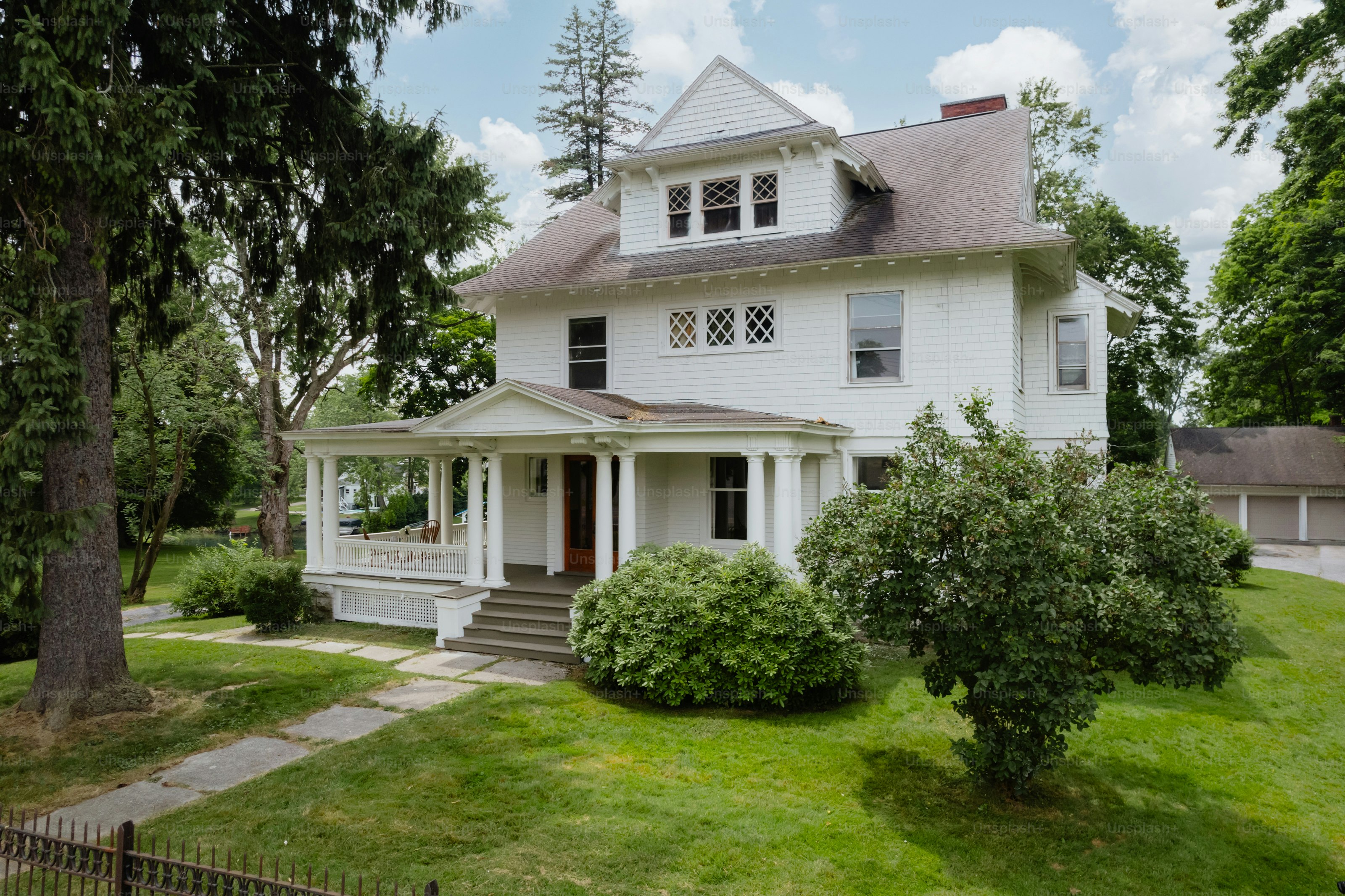 A large white house sitting on top of a lush green field