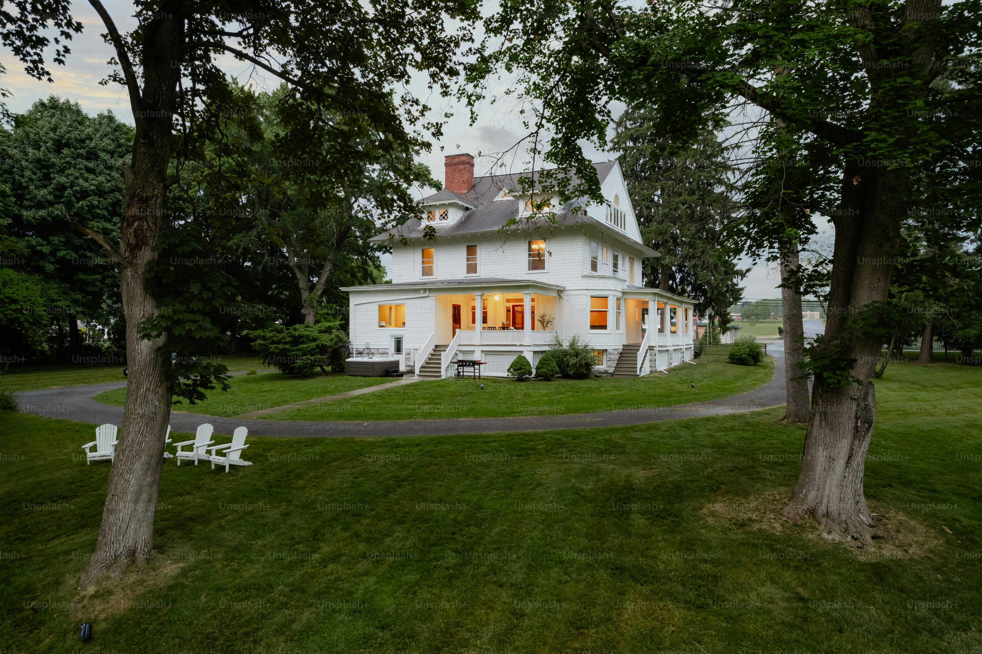 A large white house sitting on top of a lush green field