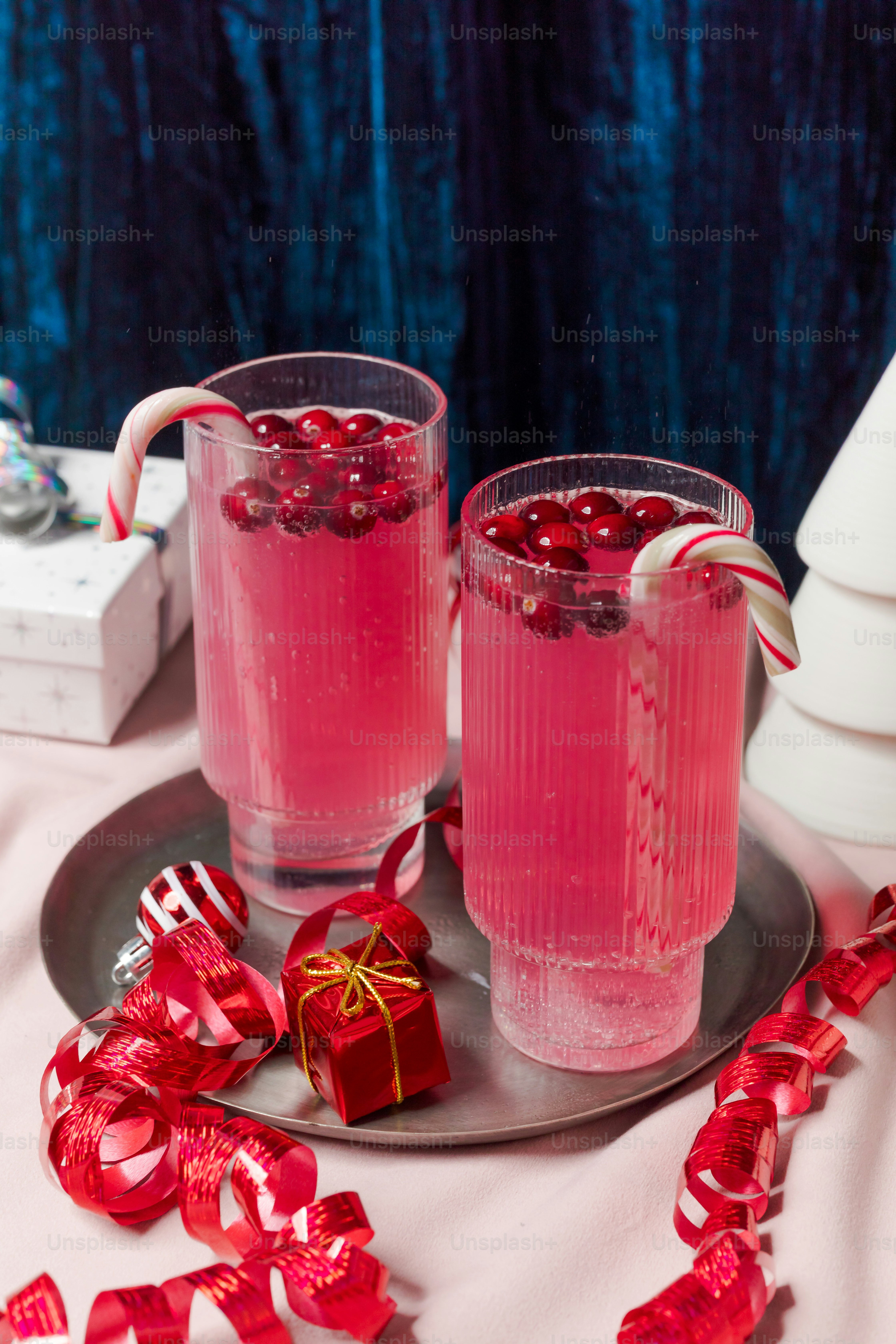 Two glasses filled with pink liquid and candy canes