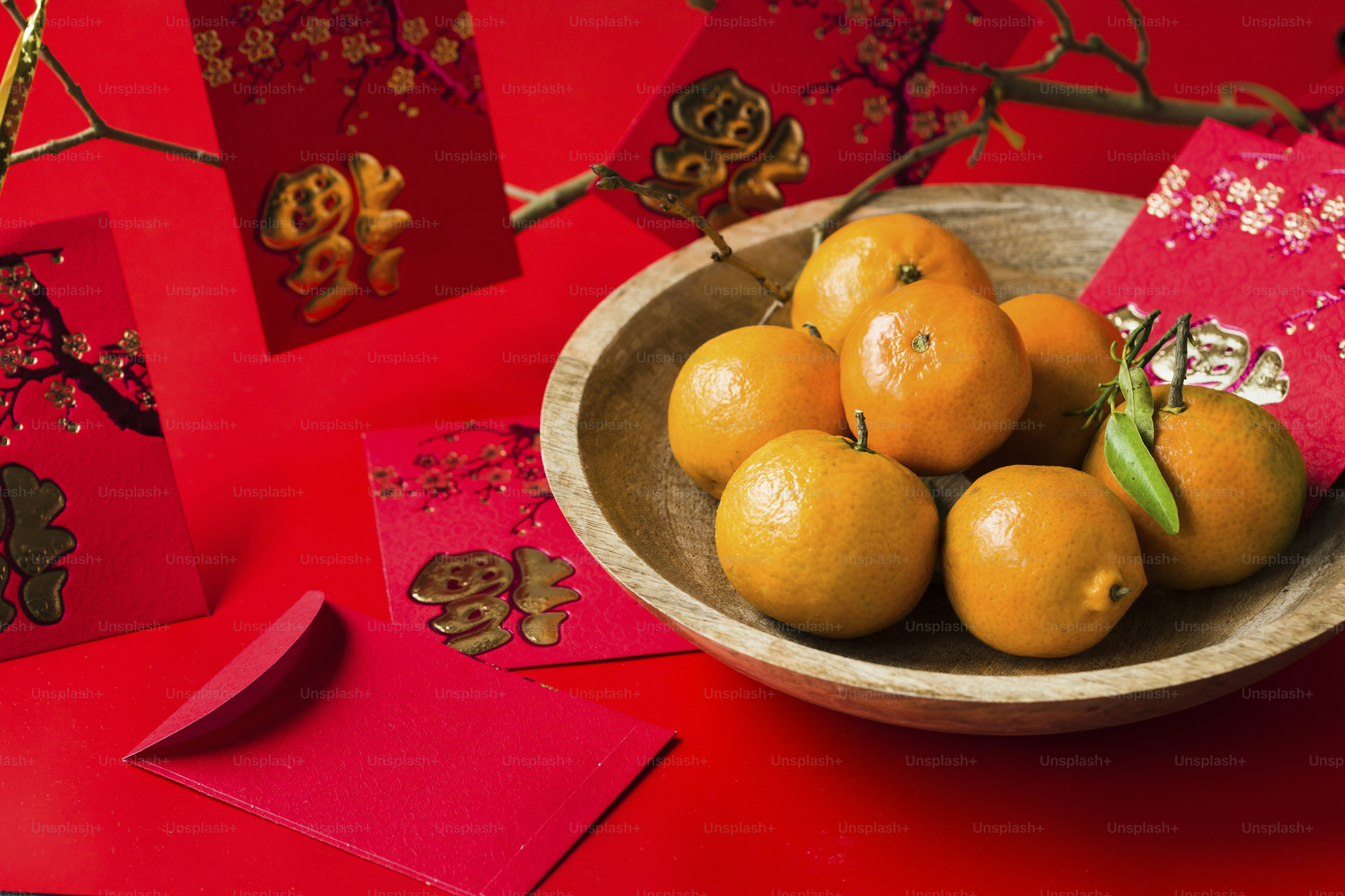 A bowl filled with oranges on top of a red table