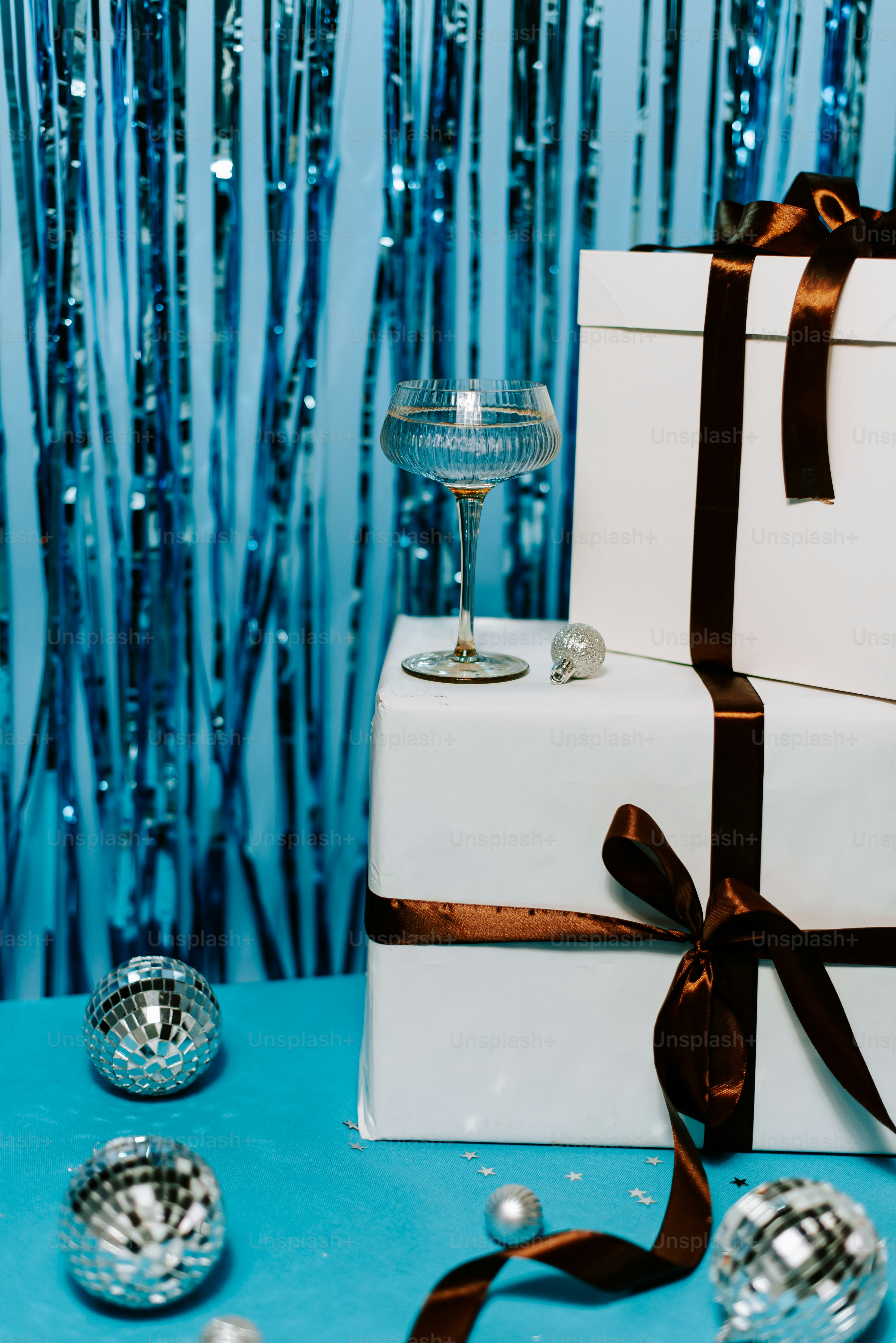 A white gift box with a brown ribbon and a wine glass