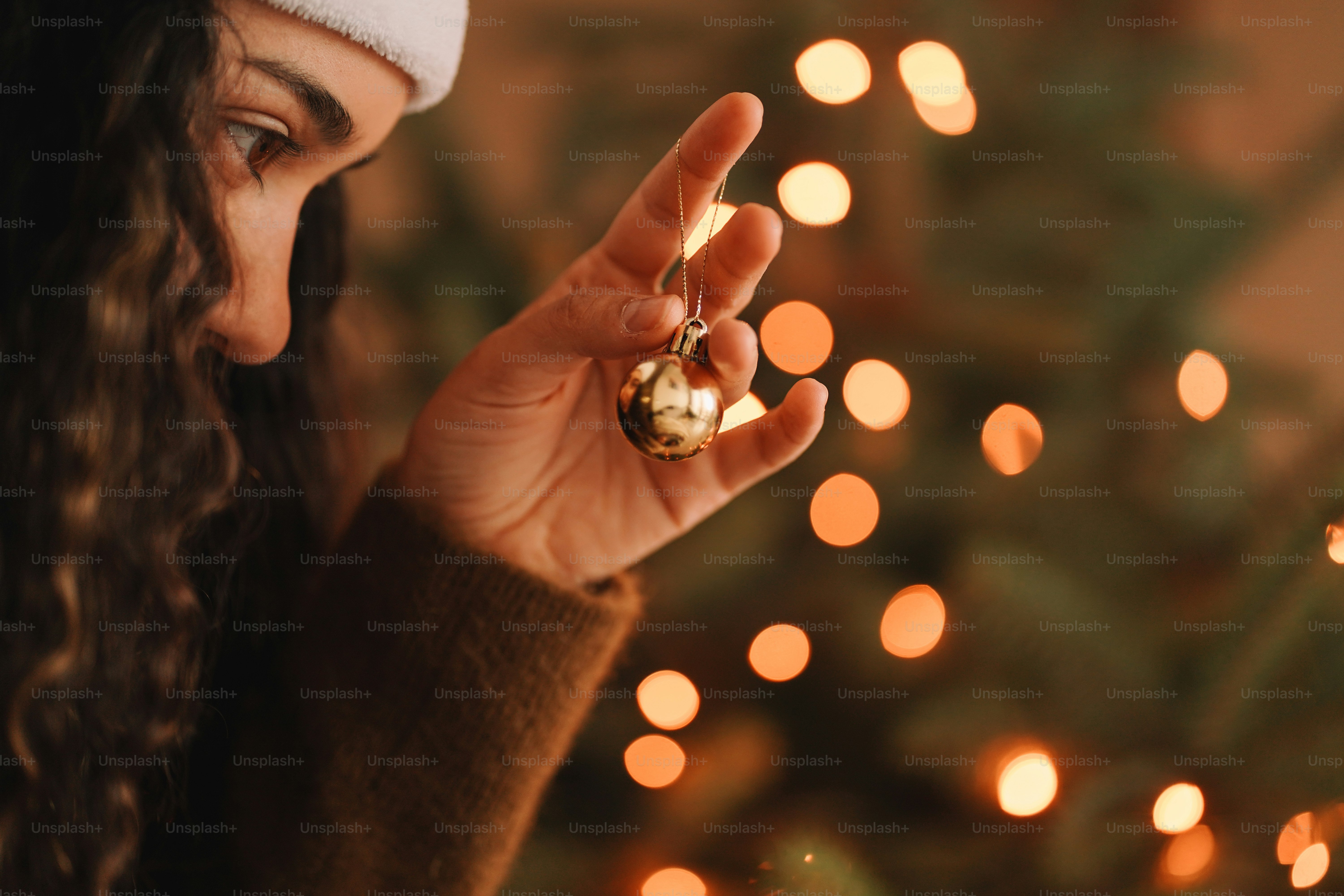 A woman wearing a santa hat holding a christmas ornament