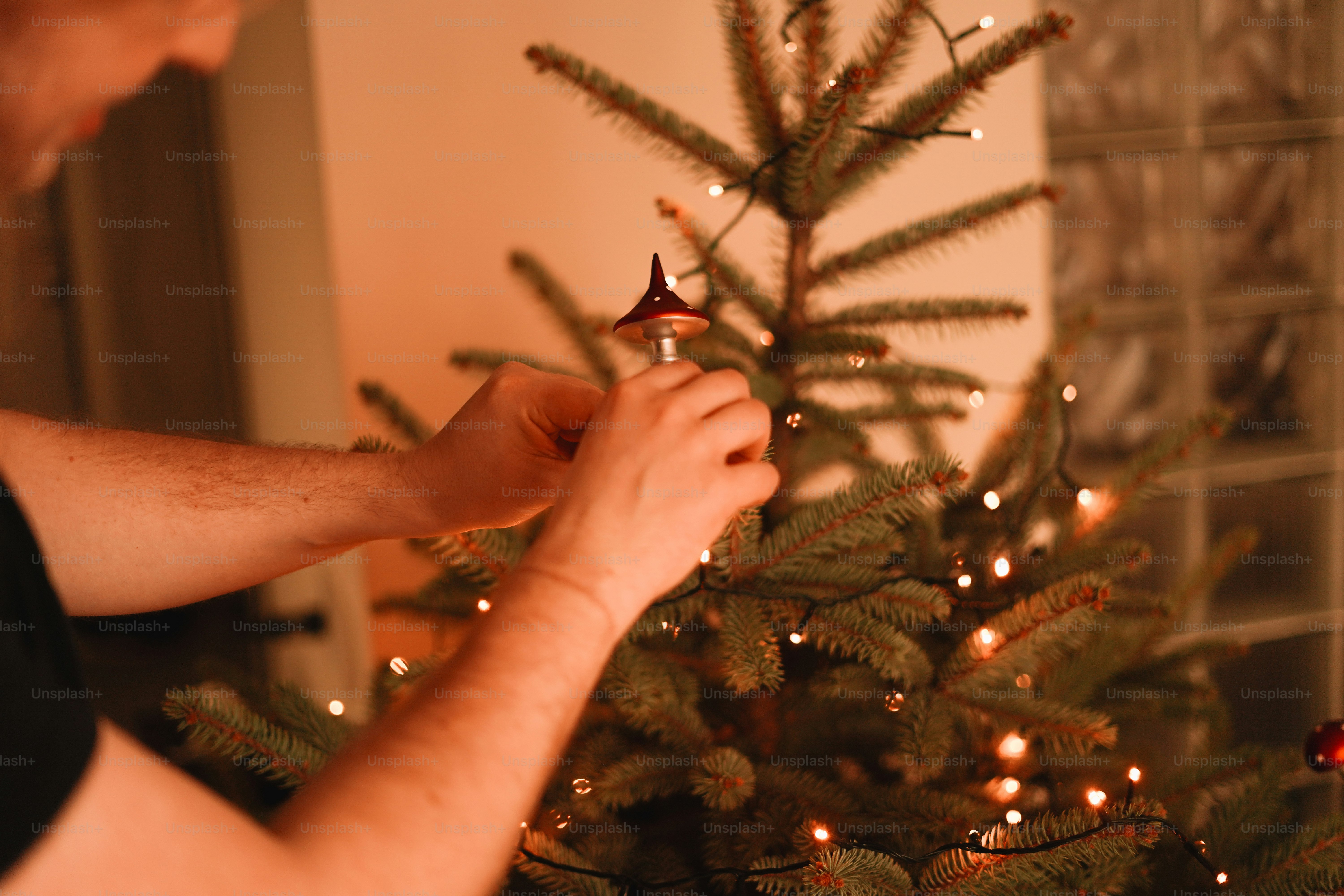 A man is decorating a christmas tree