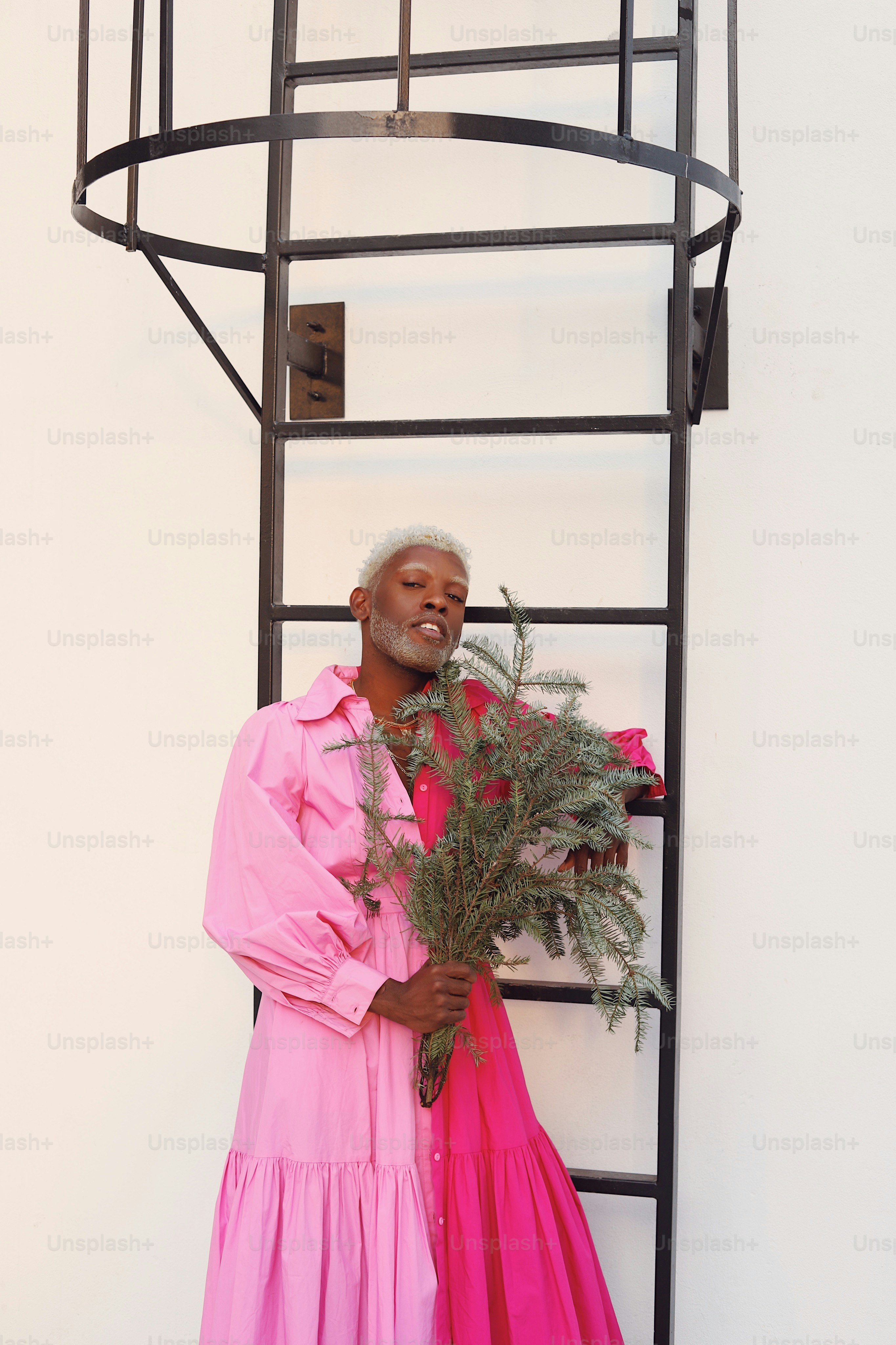 A man in a pink dress holding a bouquet of flowers