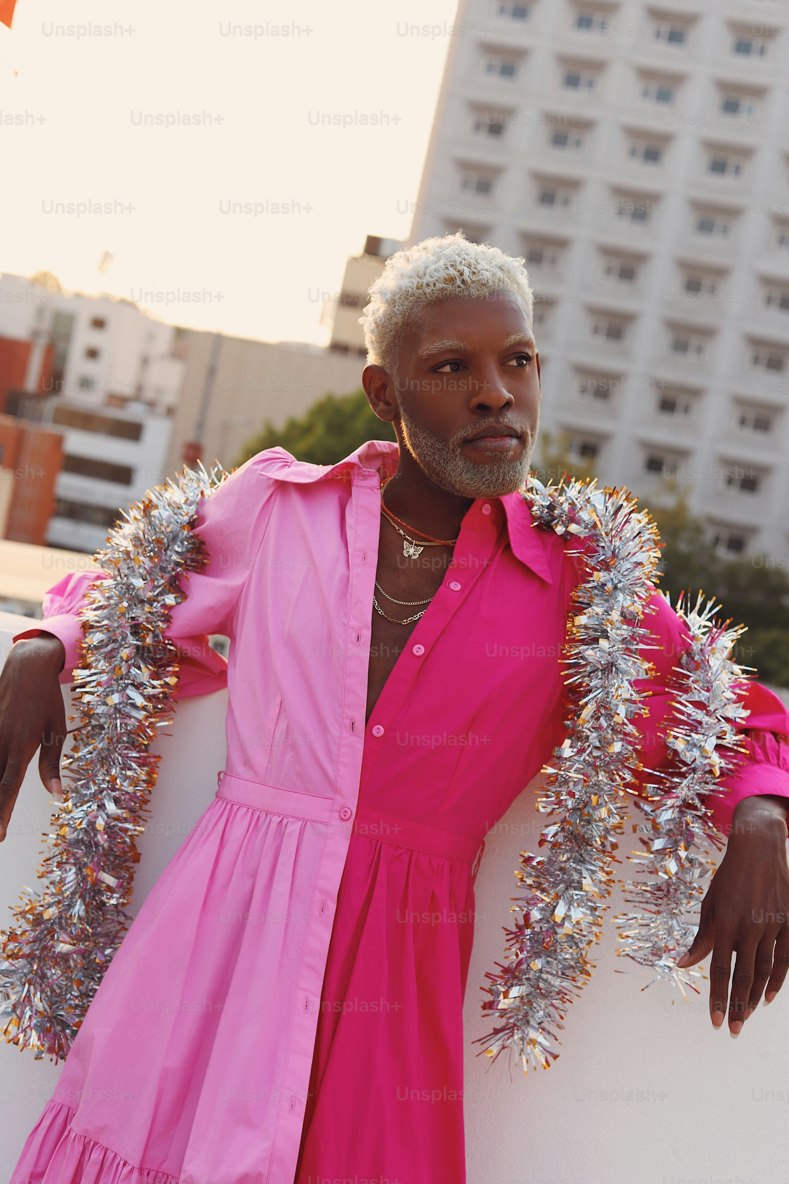 Ein Mann in einem rosa Kleid, der an einer Wand lehnt