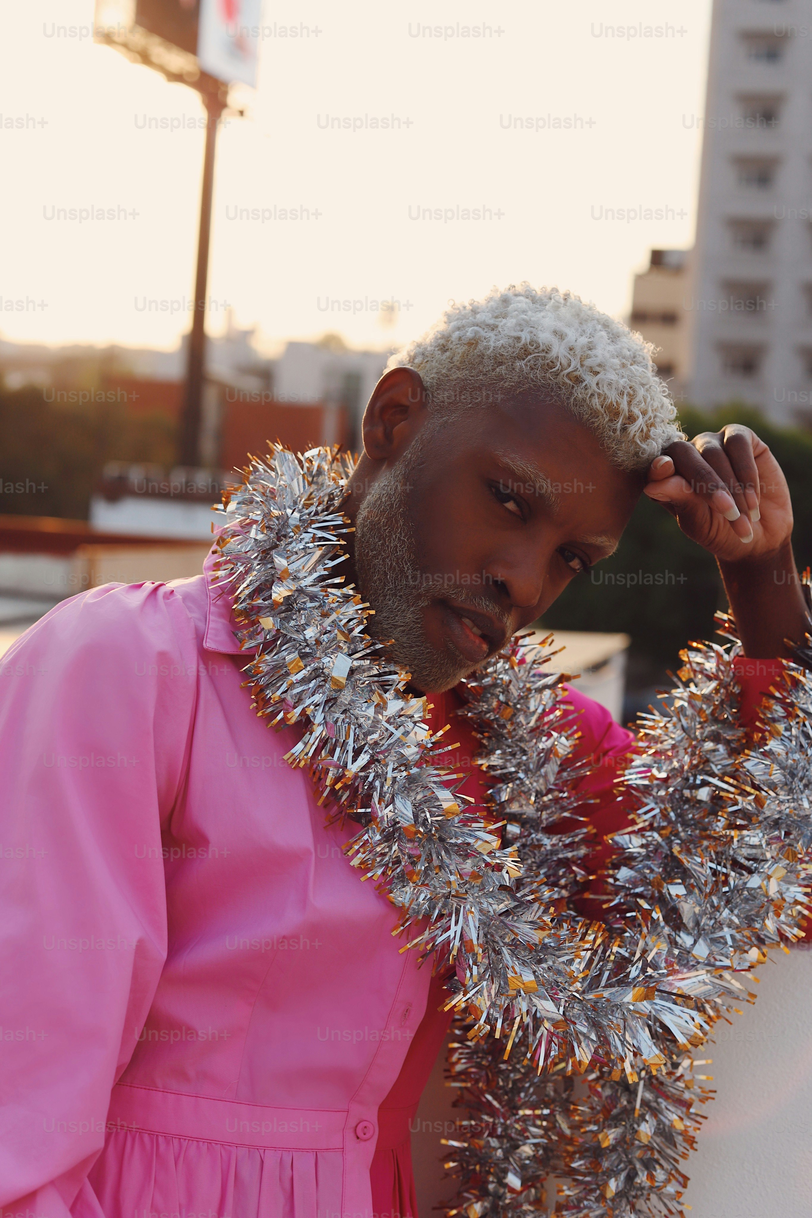 A man in a pink dress with tinsel on his neck